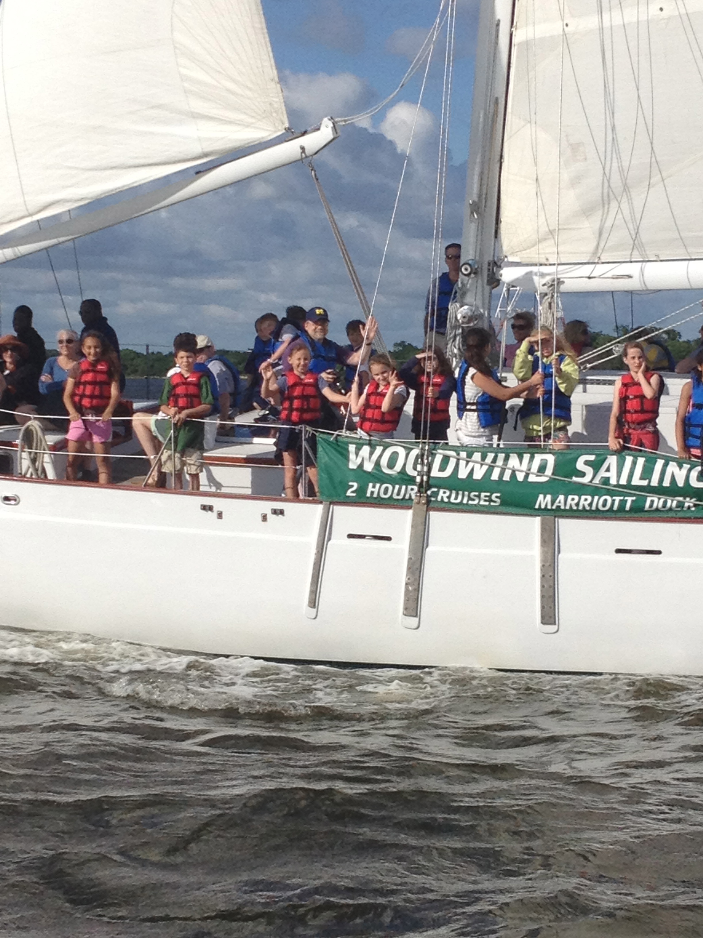 Children waving from the schooner that is breezing along