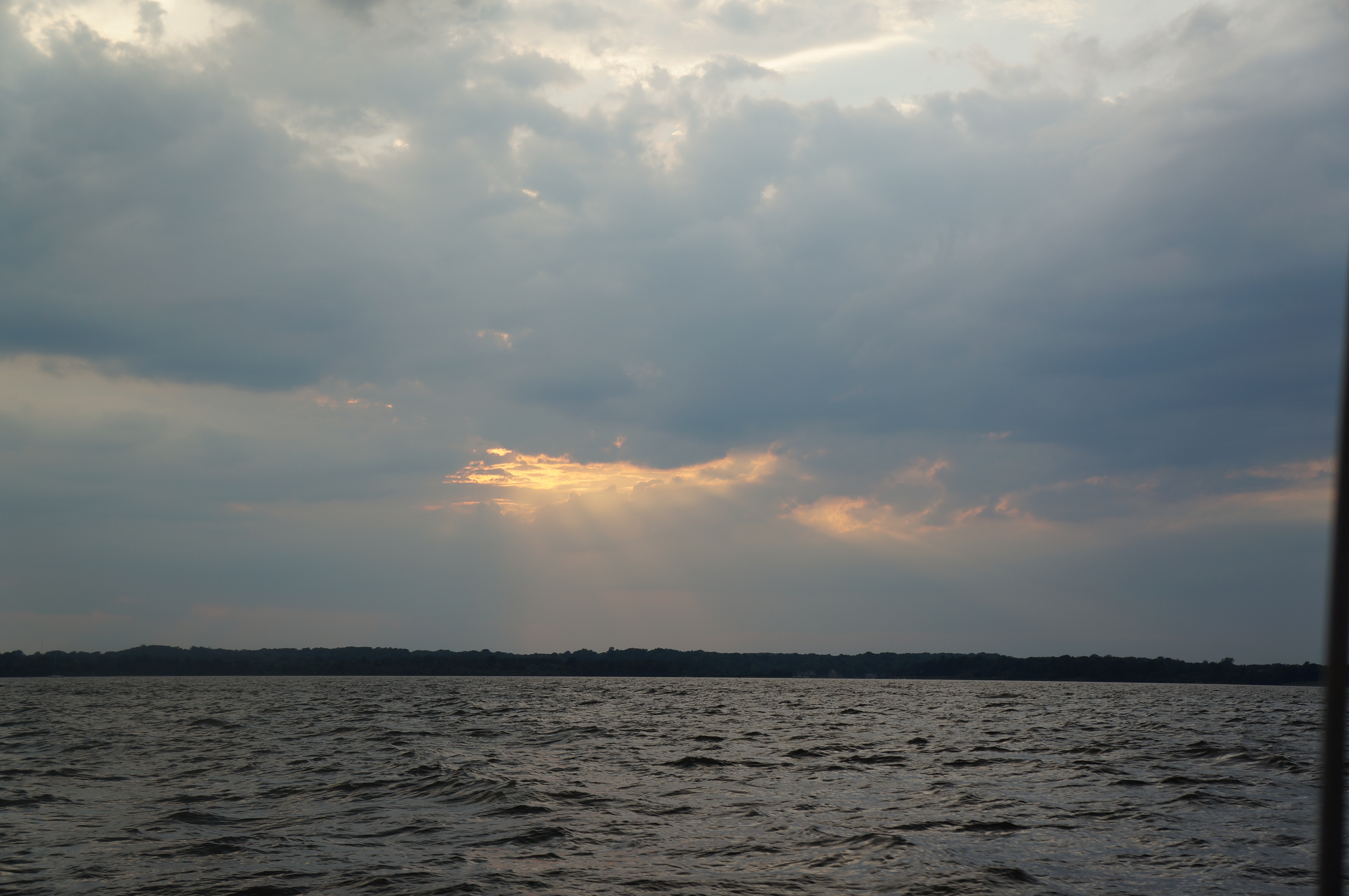 Rays of sun peaking through clouds over the water