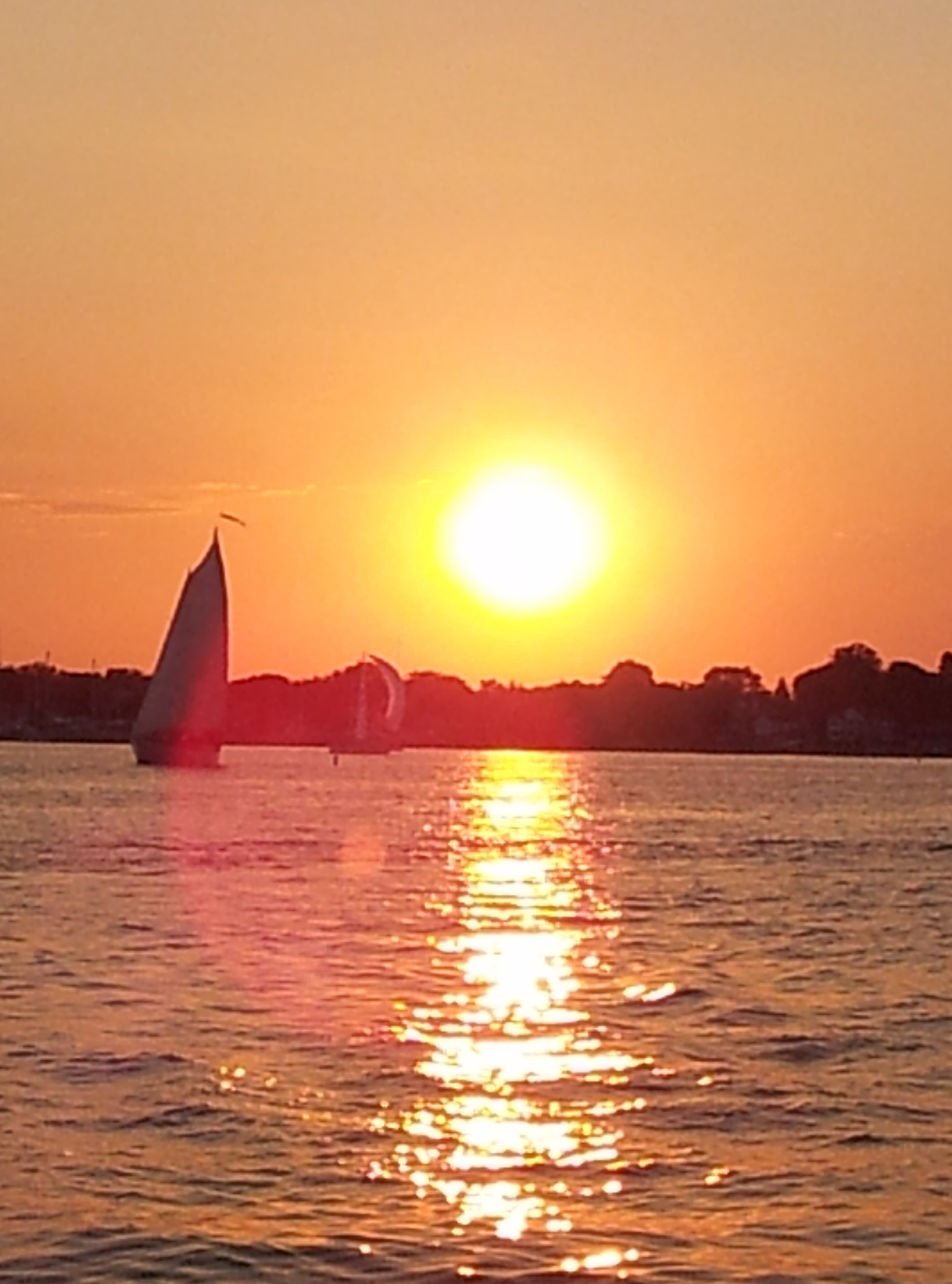 Bright ball of sun and sail boats