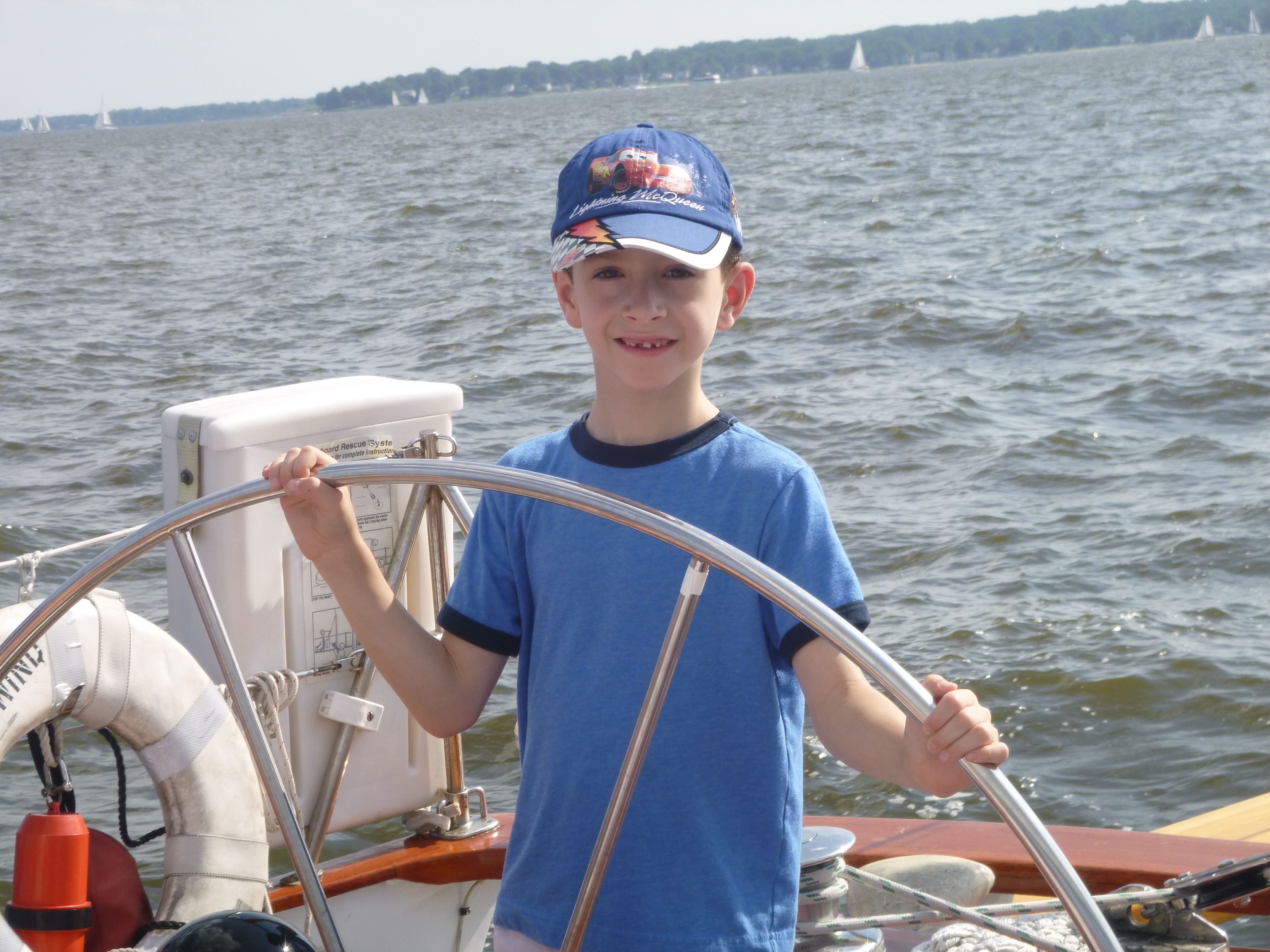 Young man in blue shirt and cap sailing the boat