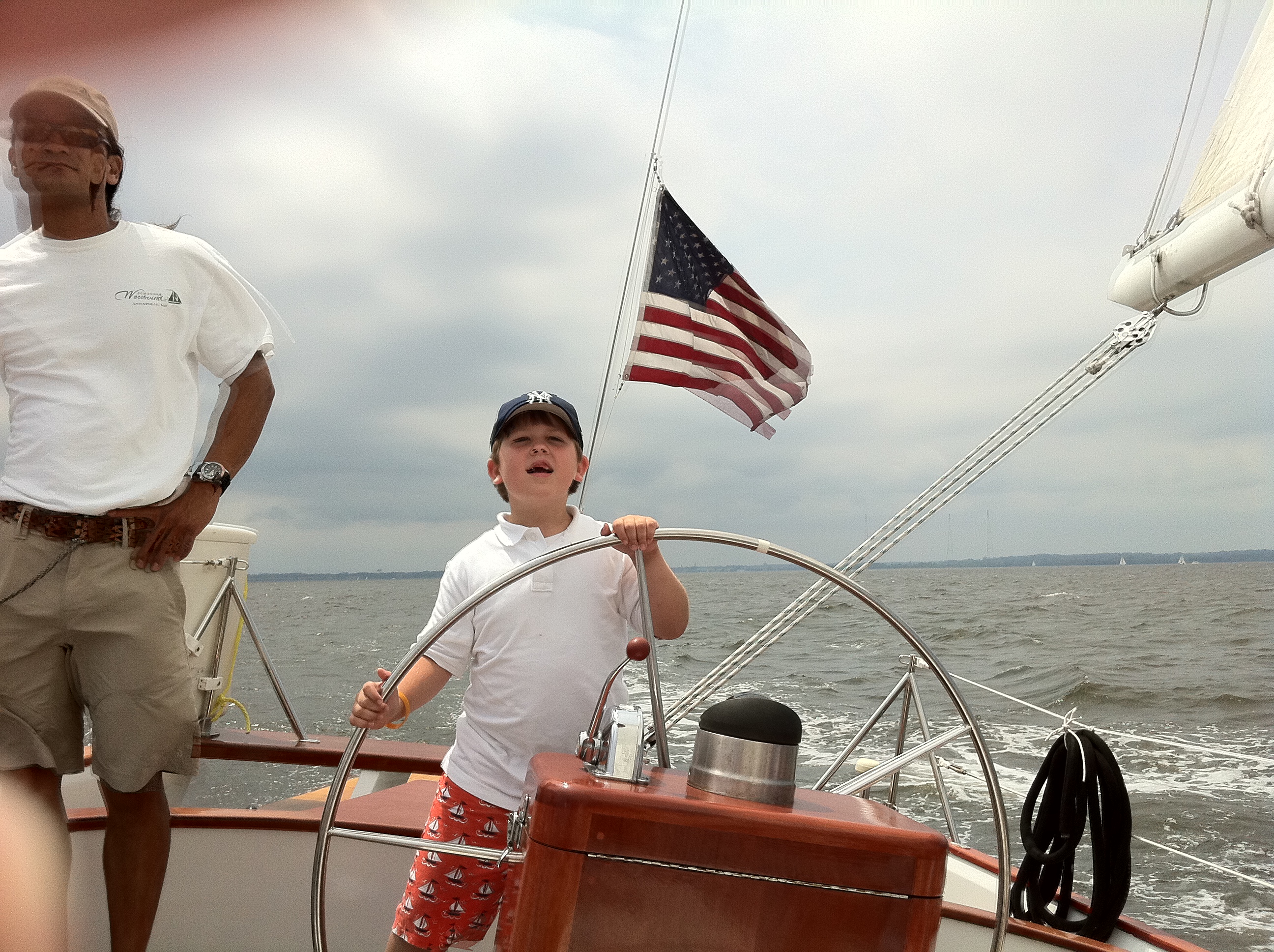 Young boy steering the schooner with a breeze blowing the American Flag
