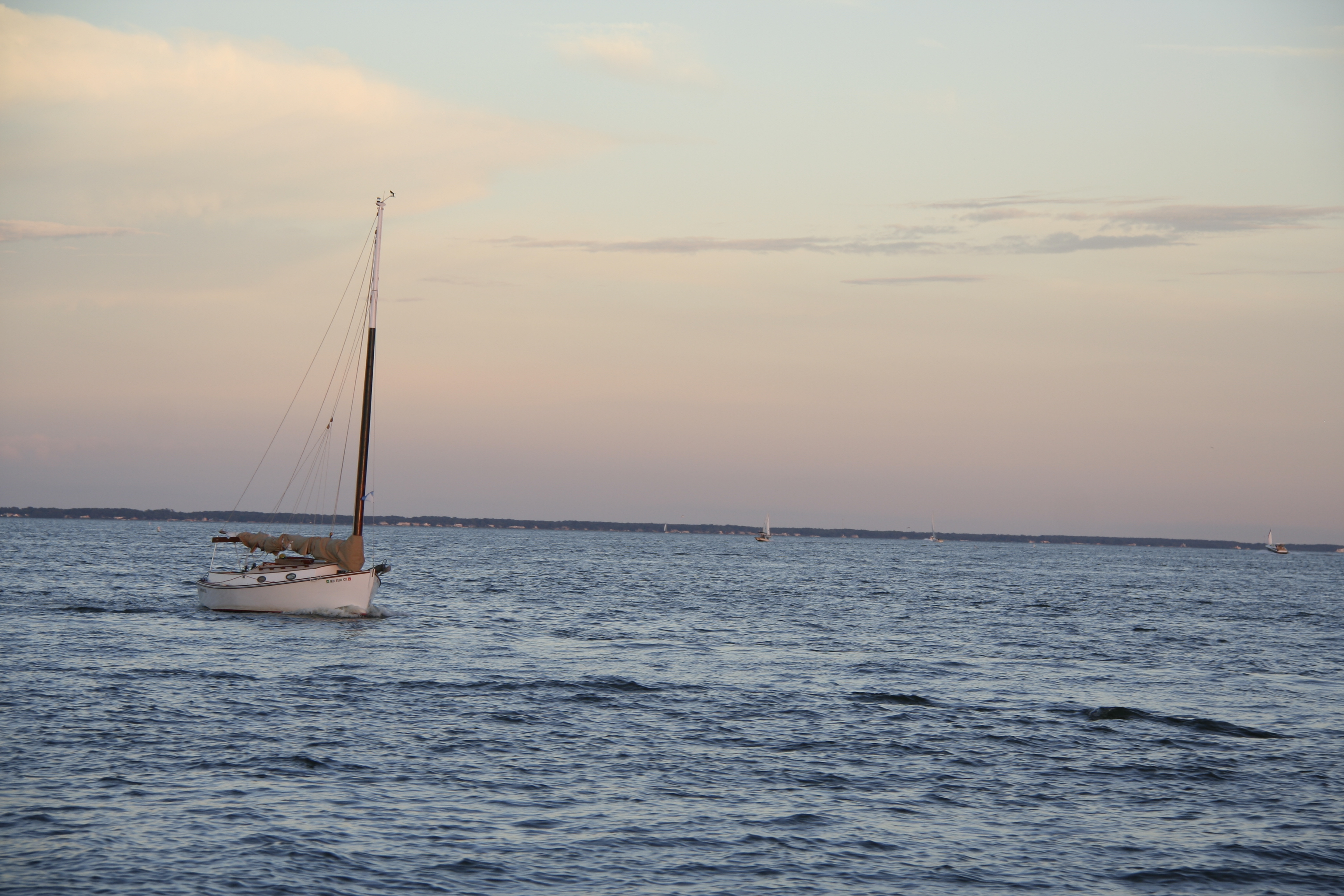 Sailboat moored on blue waters with a pink sunset
