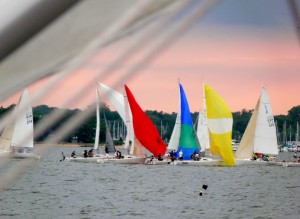 J 80 fleet races to the downwind mark.  The sunset is starting to build its colors.