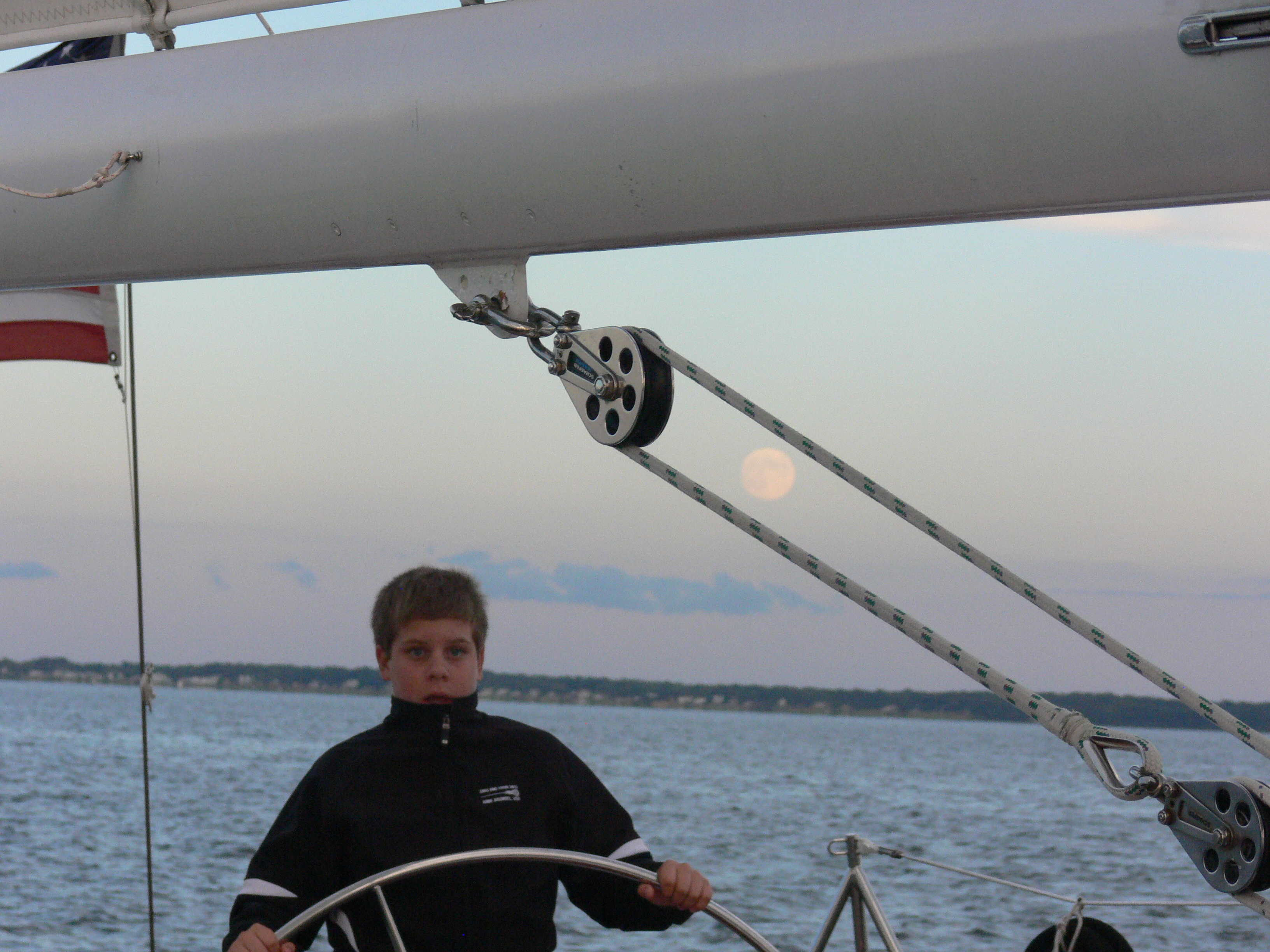 Young man named Adam sailing the schooner with a full moon over his shoulder