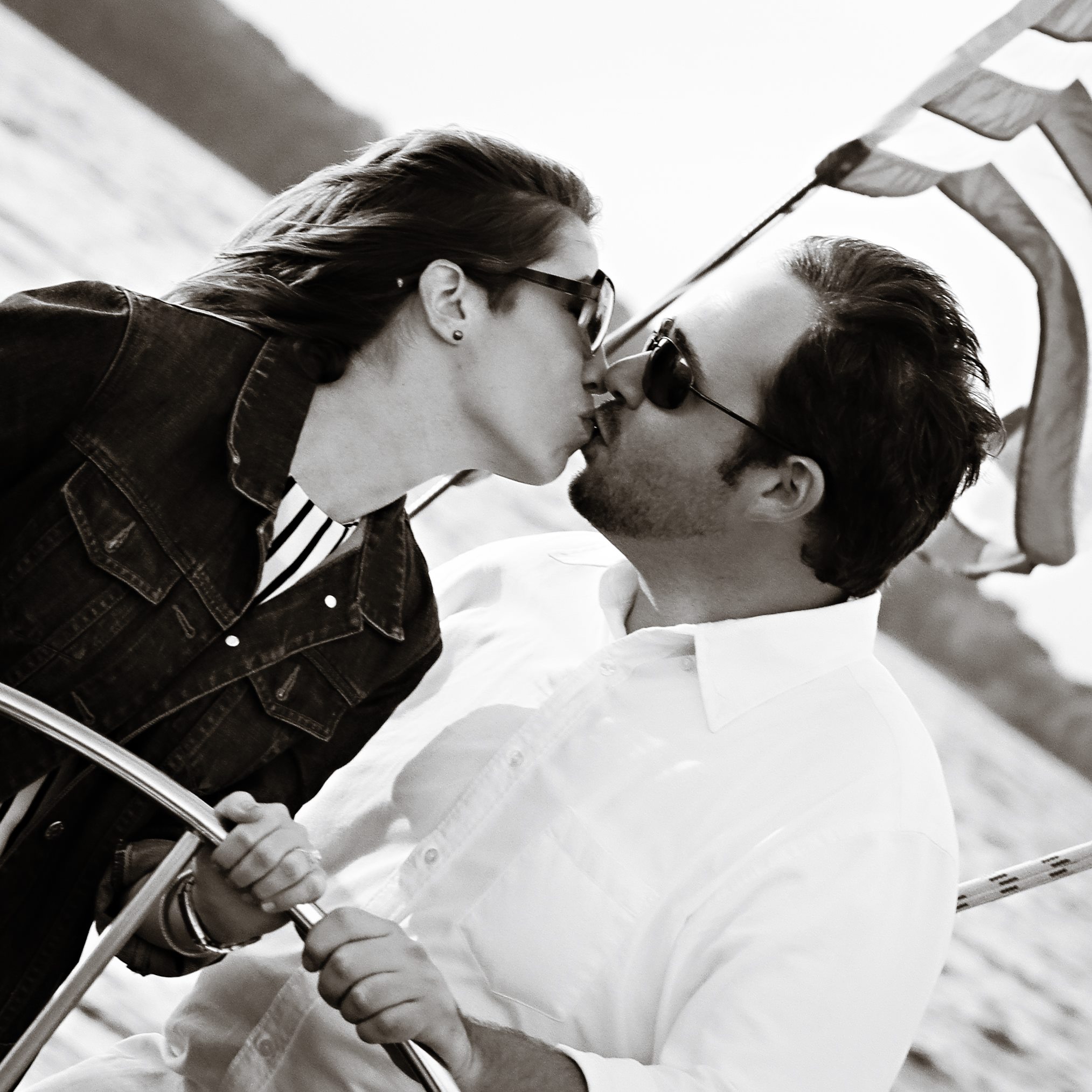 Couple in black and white photo kissing and steering the helm