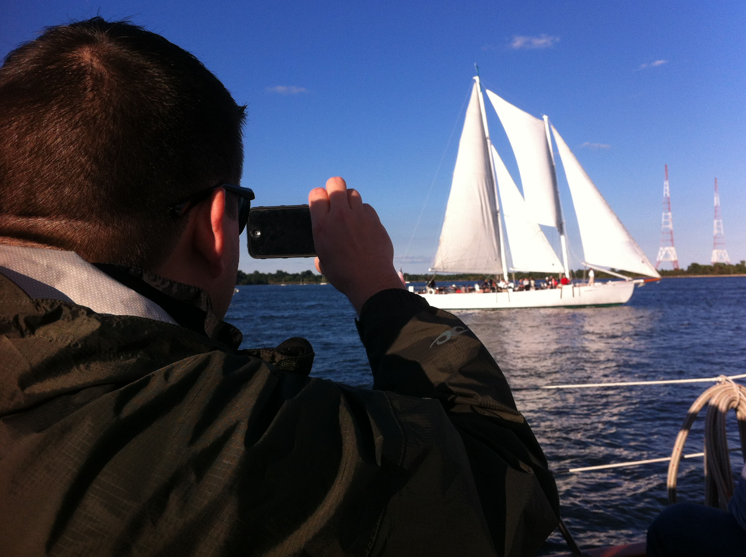 Man taking picture of schooner from other schooner on his phone