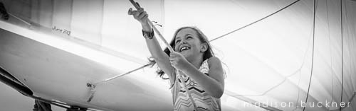 Black and white photo of little girl helping to raise the sails