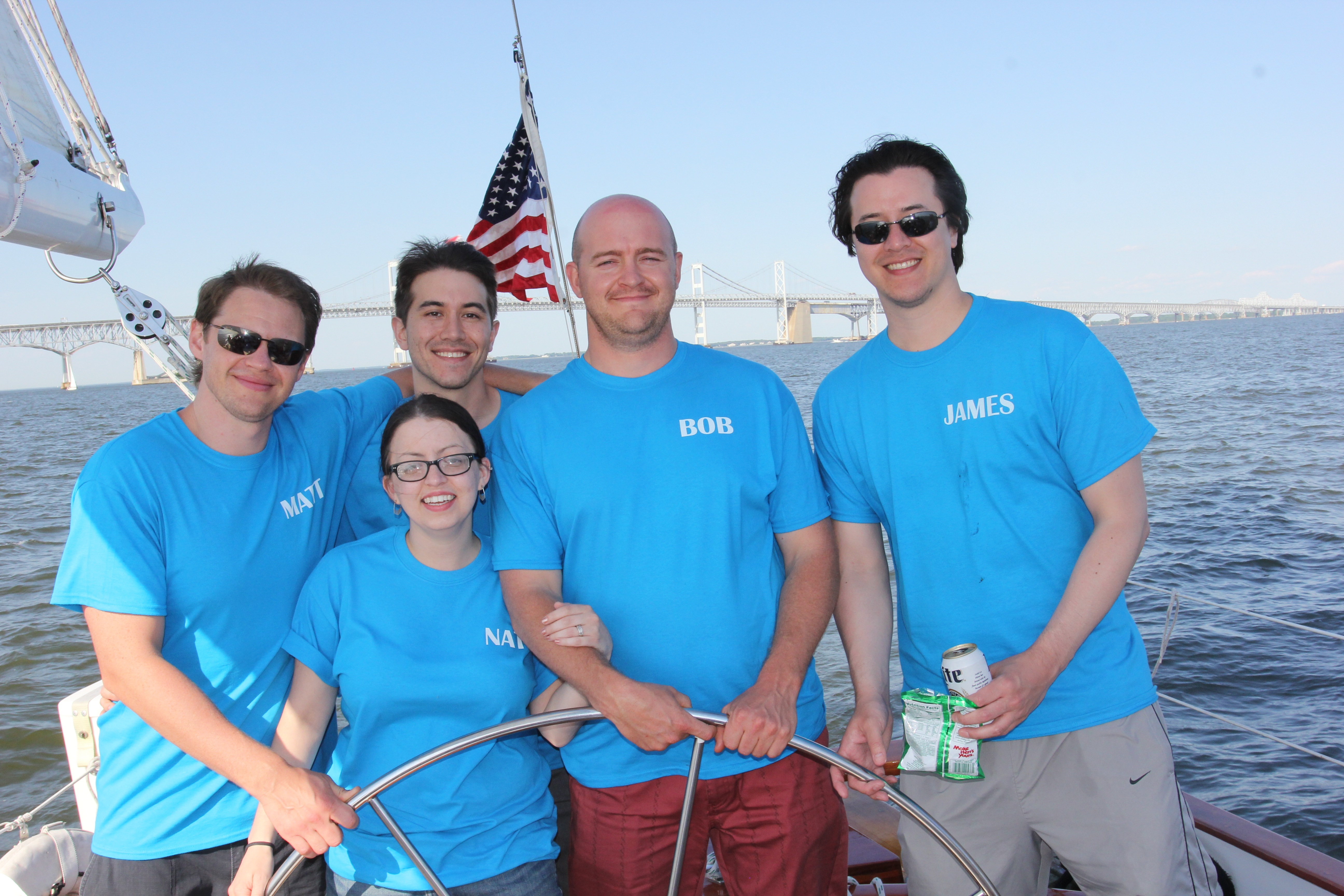 Group of five guests in blue t-shirts sailing the schooner together