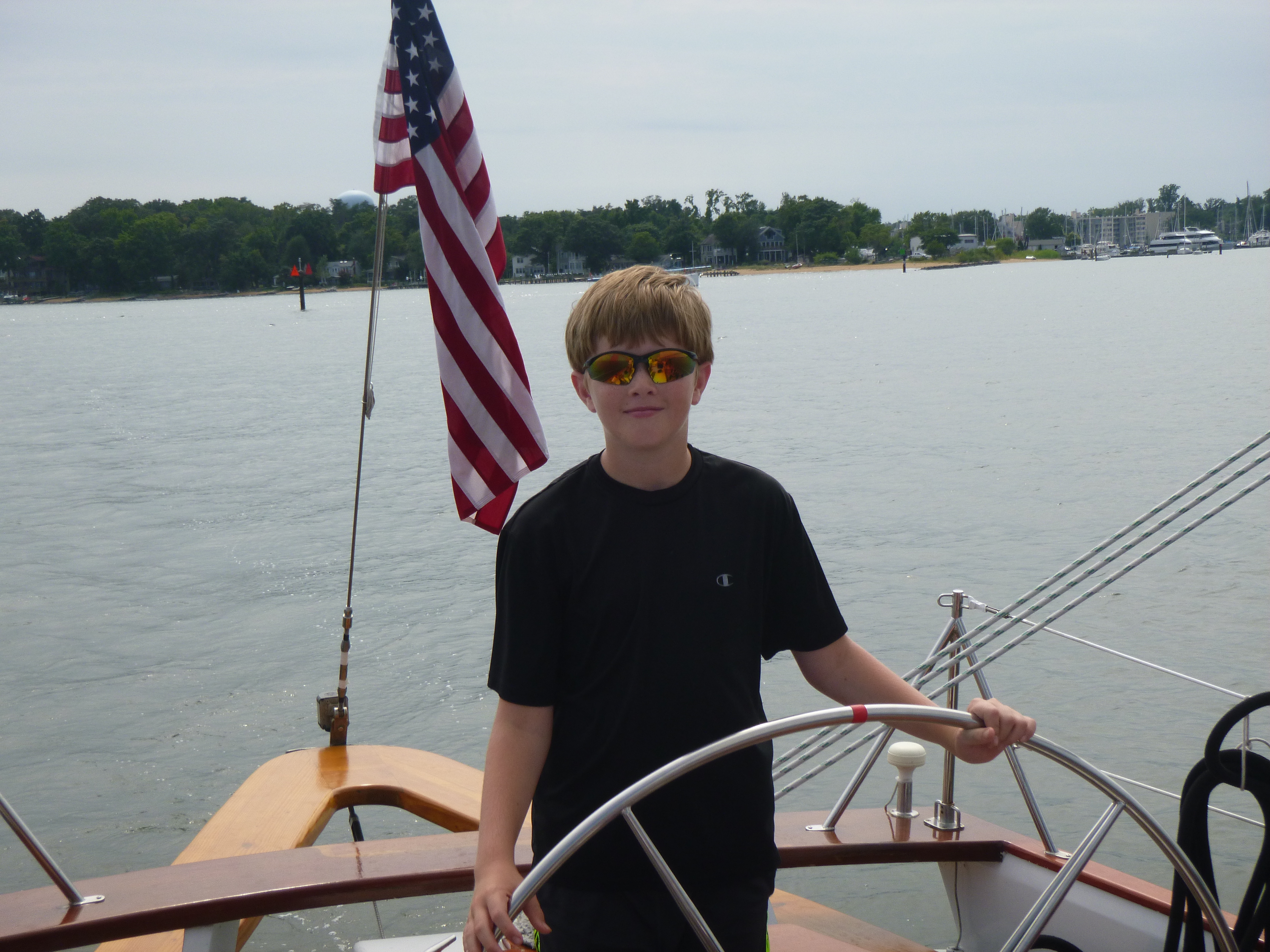 Young man in sunglasses at the helm of the Schooner Woodwind