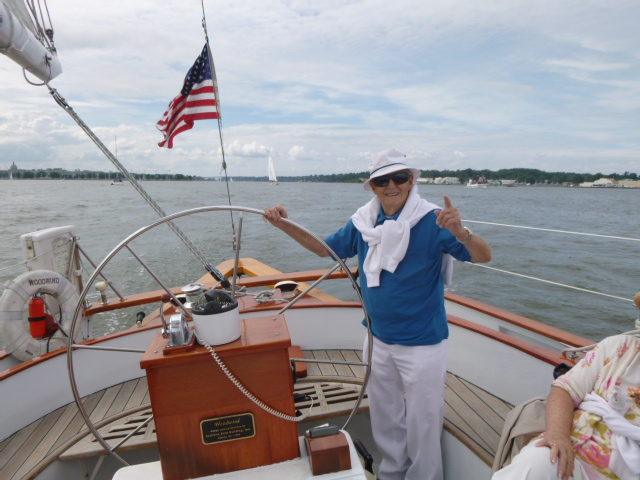 Gentleman in white hat and blue shirt at the helm of Schooner Woodwind