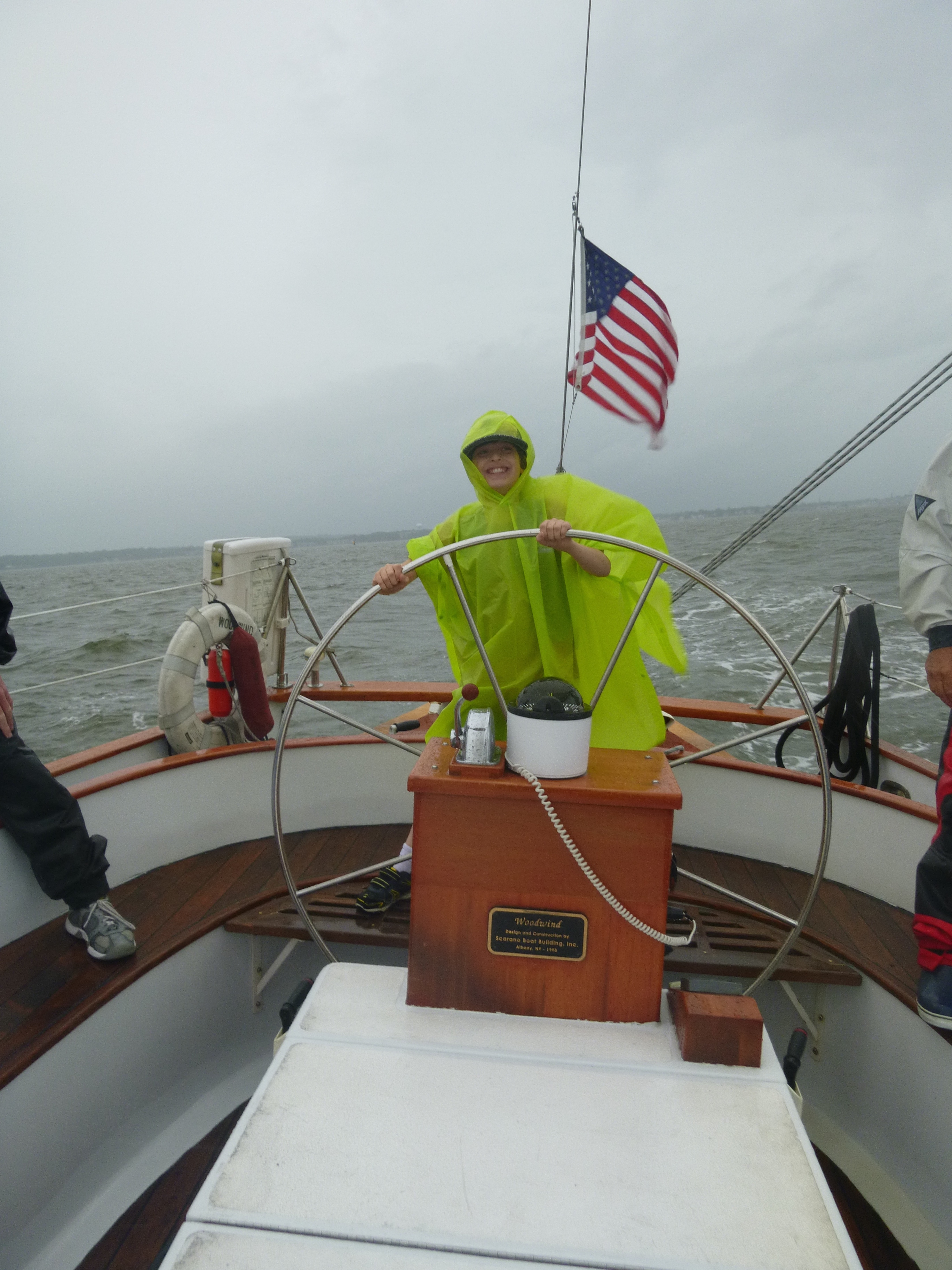 Guest sailing the schooner with a bright green poncho on a stormy day