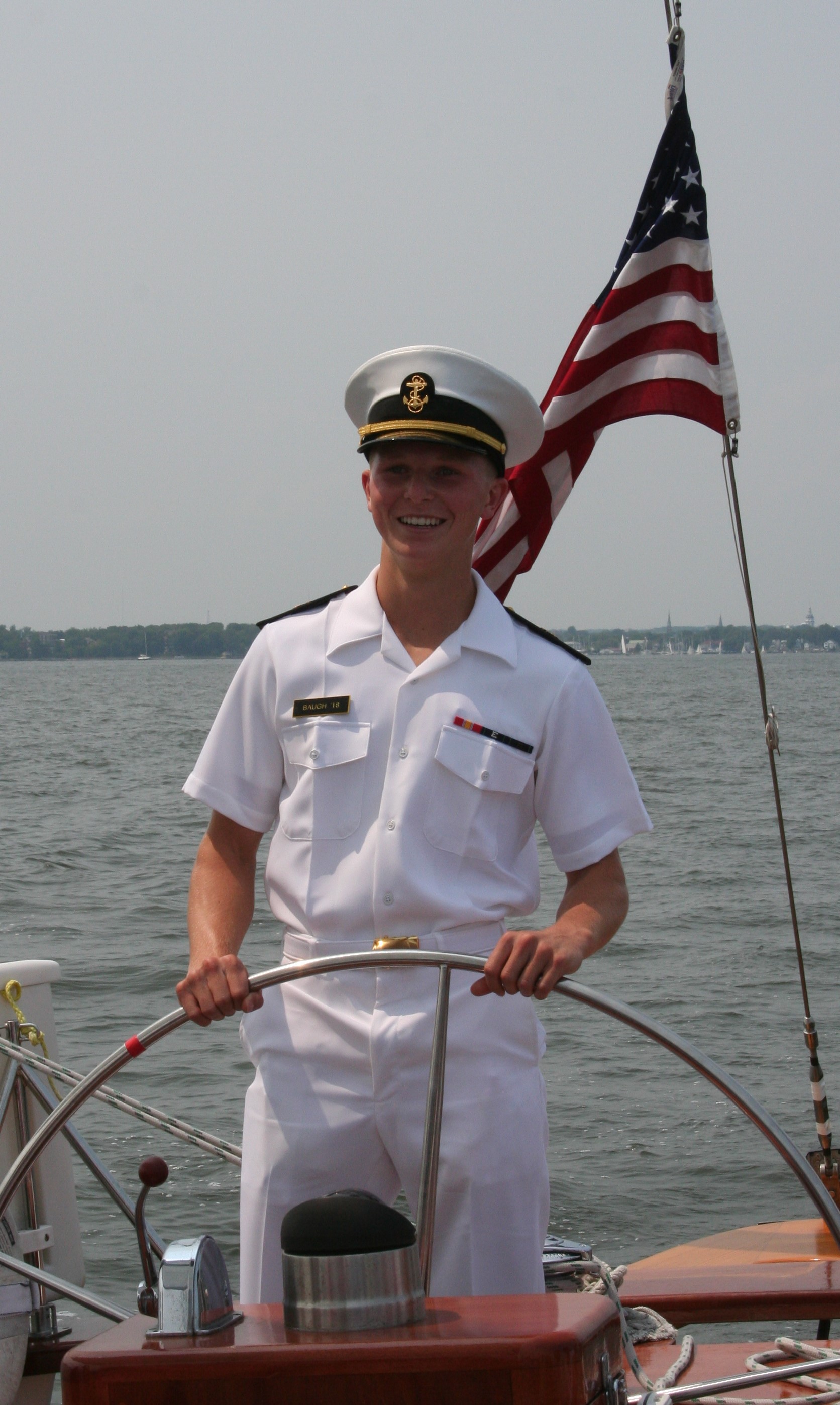 Man in USNA uniform steering the schooner