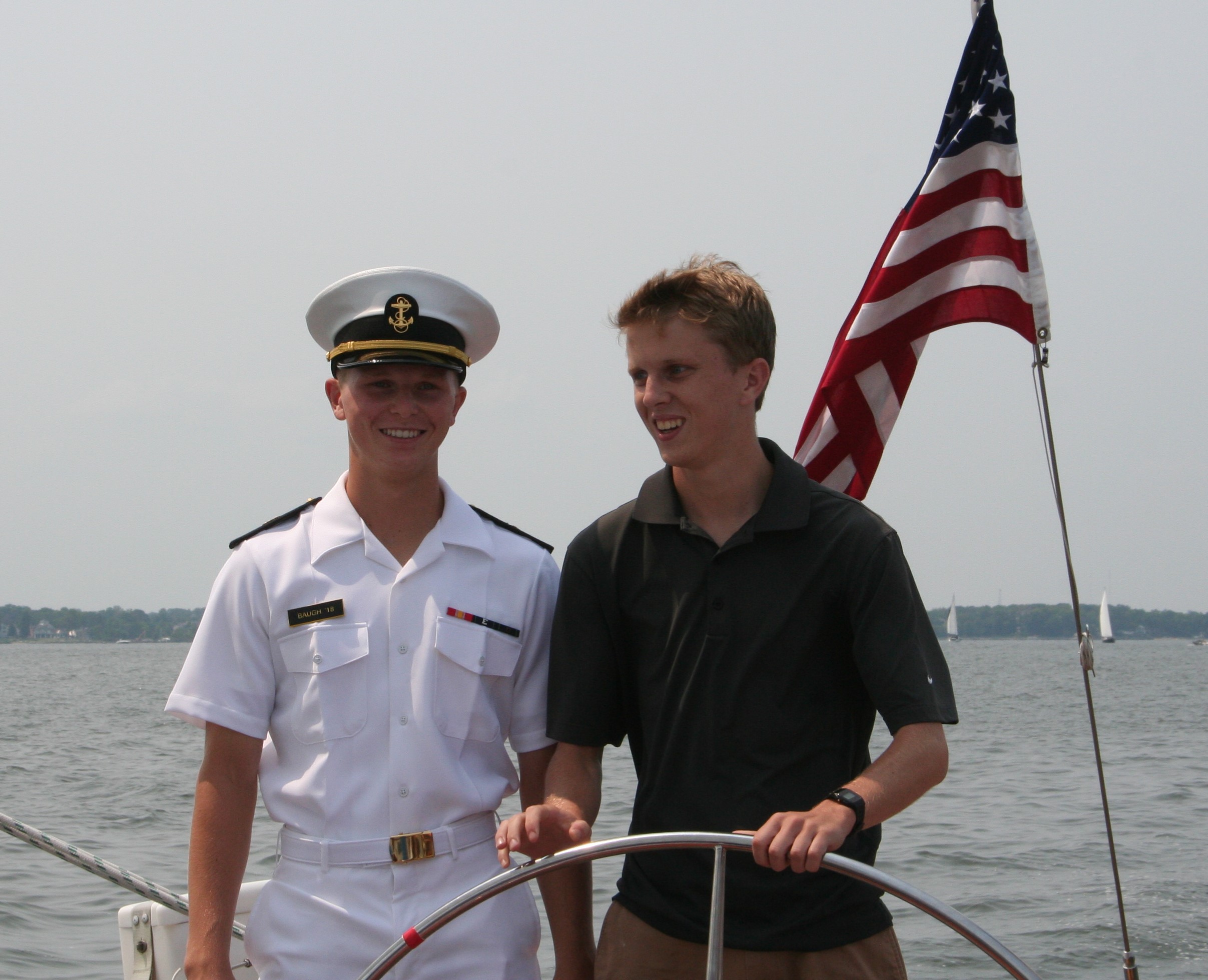One man in USNA uniform and one guest steering the schooner together