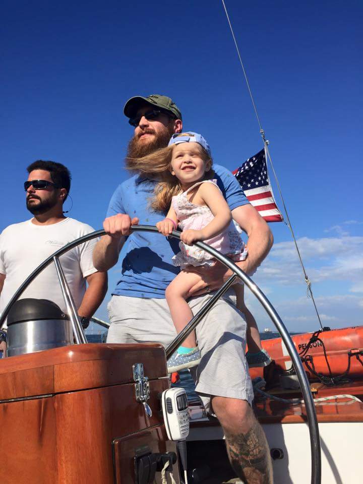 Man holding daughter and steering the schooner