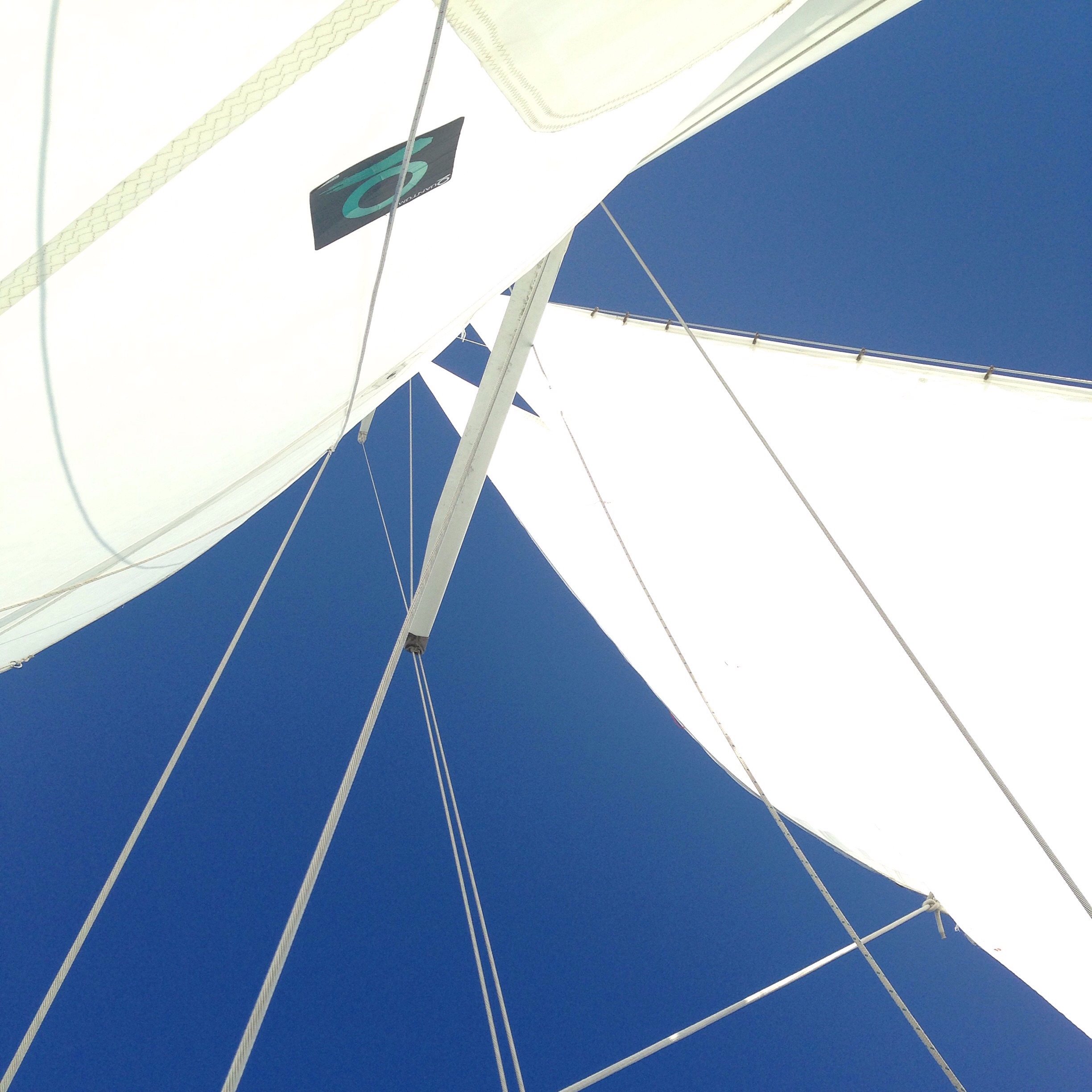 Looking up at pure blue skies through the schooners white sails