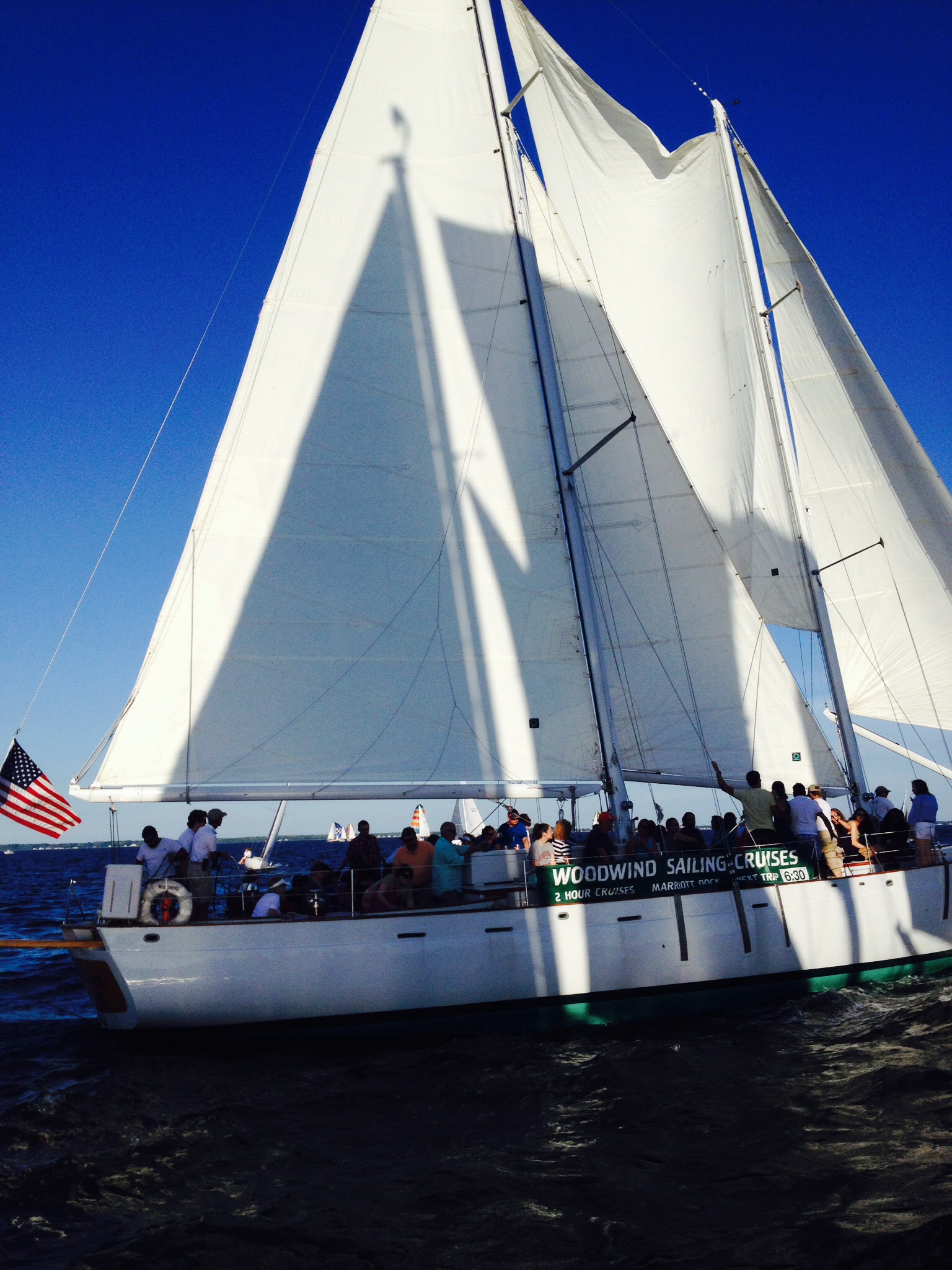 White sails of the schooner in full sail against bright blue skies