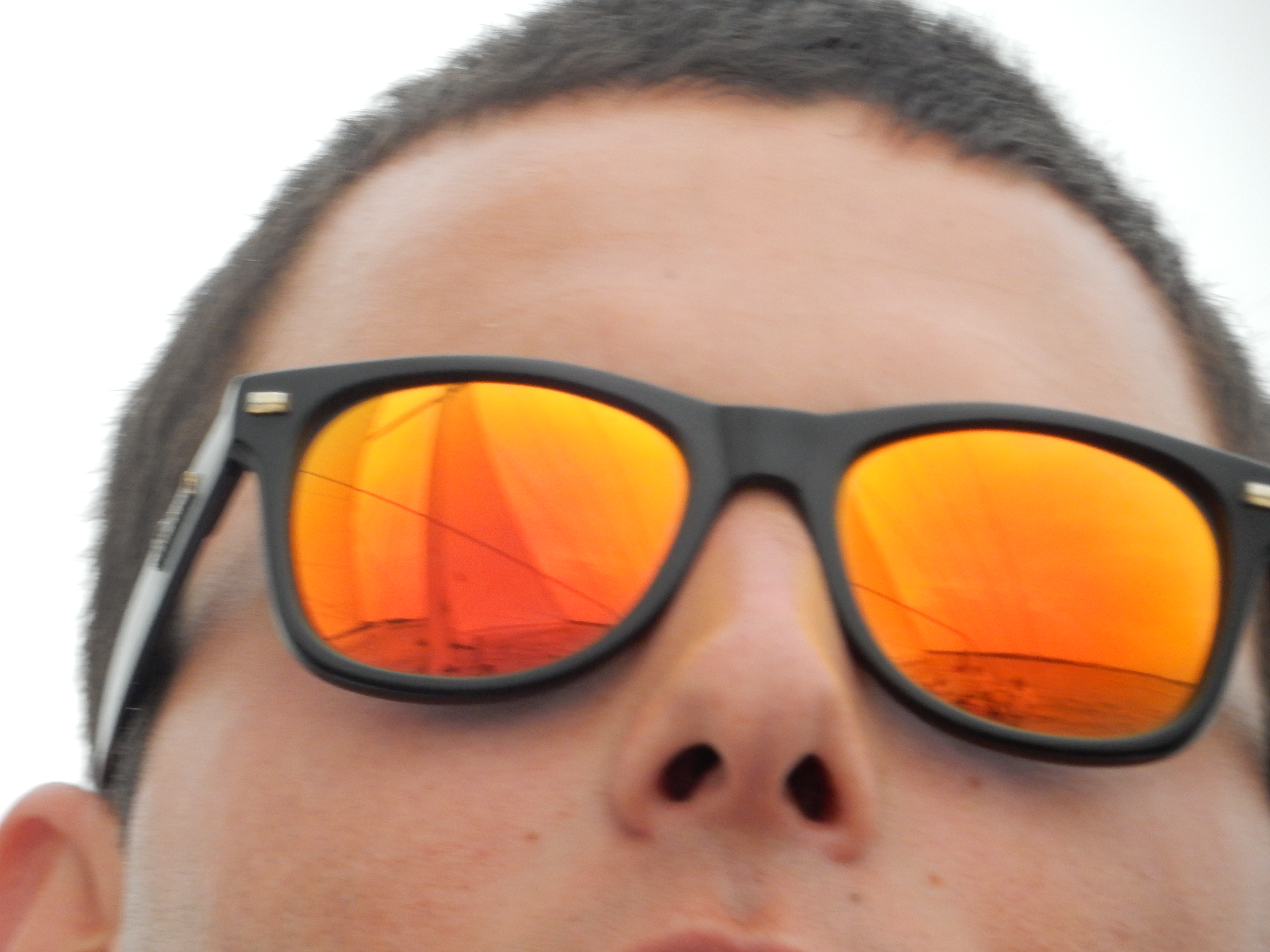 Reflections of the schooner in a man's orange sunglasses