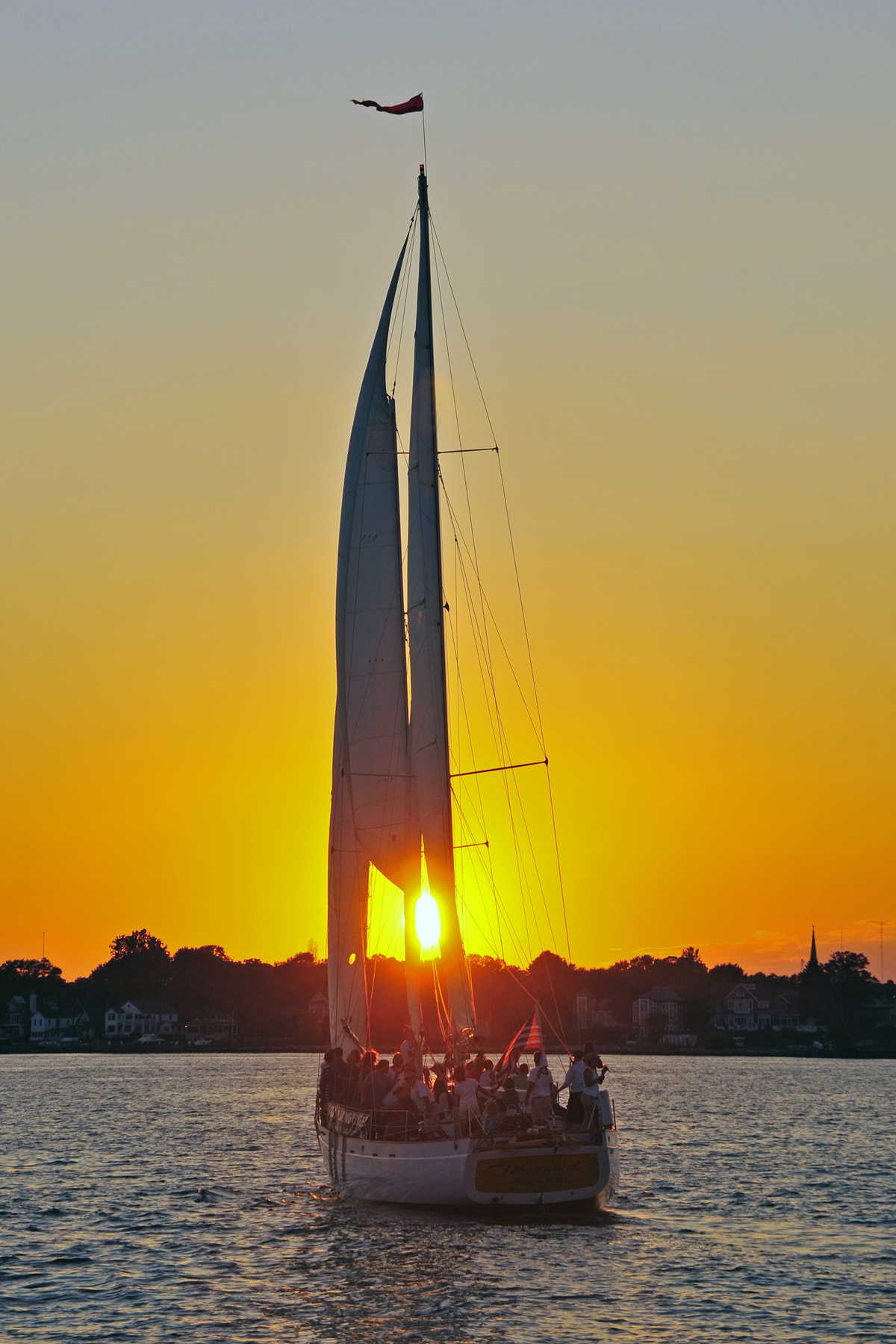 Schooner sailing into a bright yellow sunset with blue waters