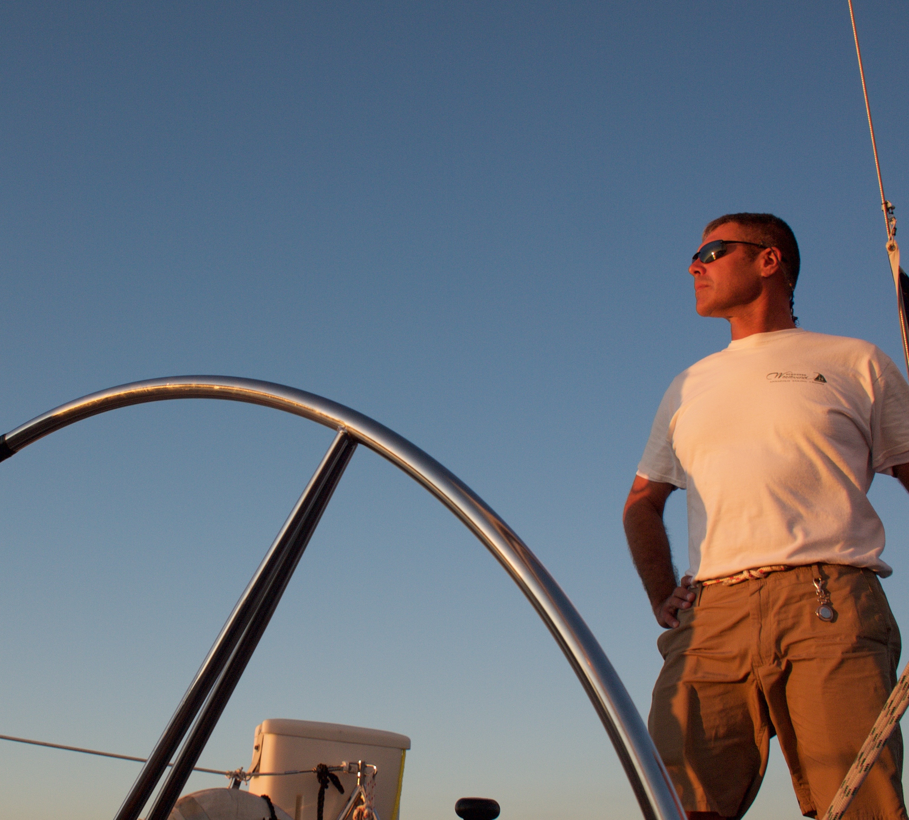 Captain at the helm 0f the schooner on a blue sky day