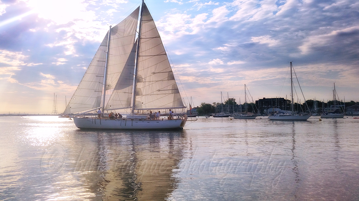 Golden Hour silhouette around the schooner on clear calm water by Bill Tongue