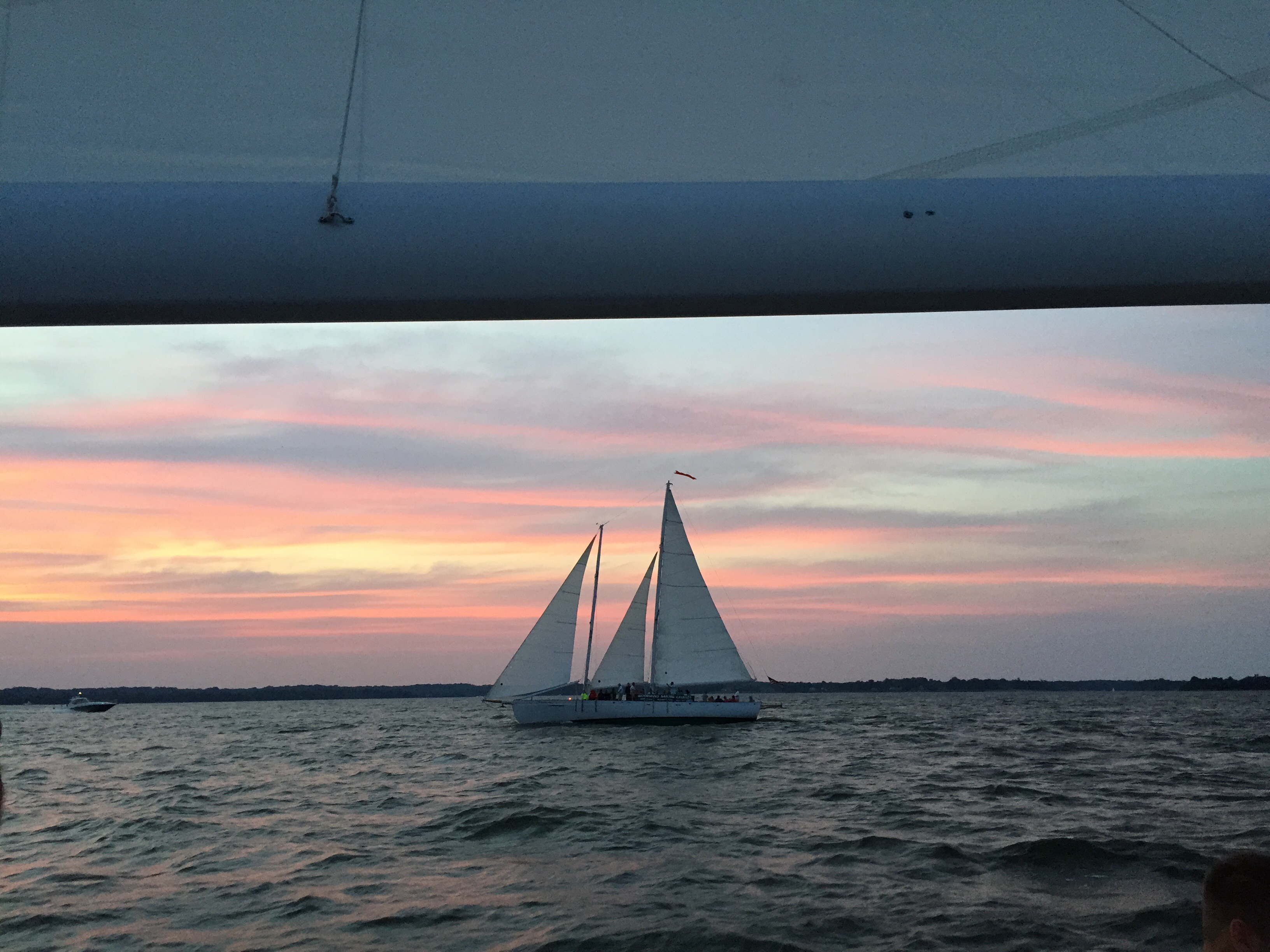 Pink blue and yellow Sunset framing schooner on the water