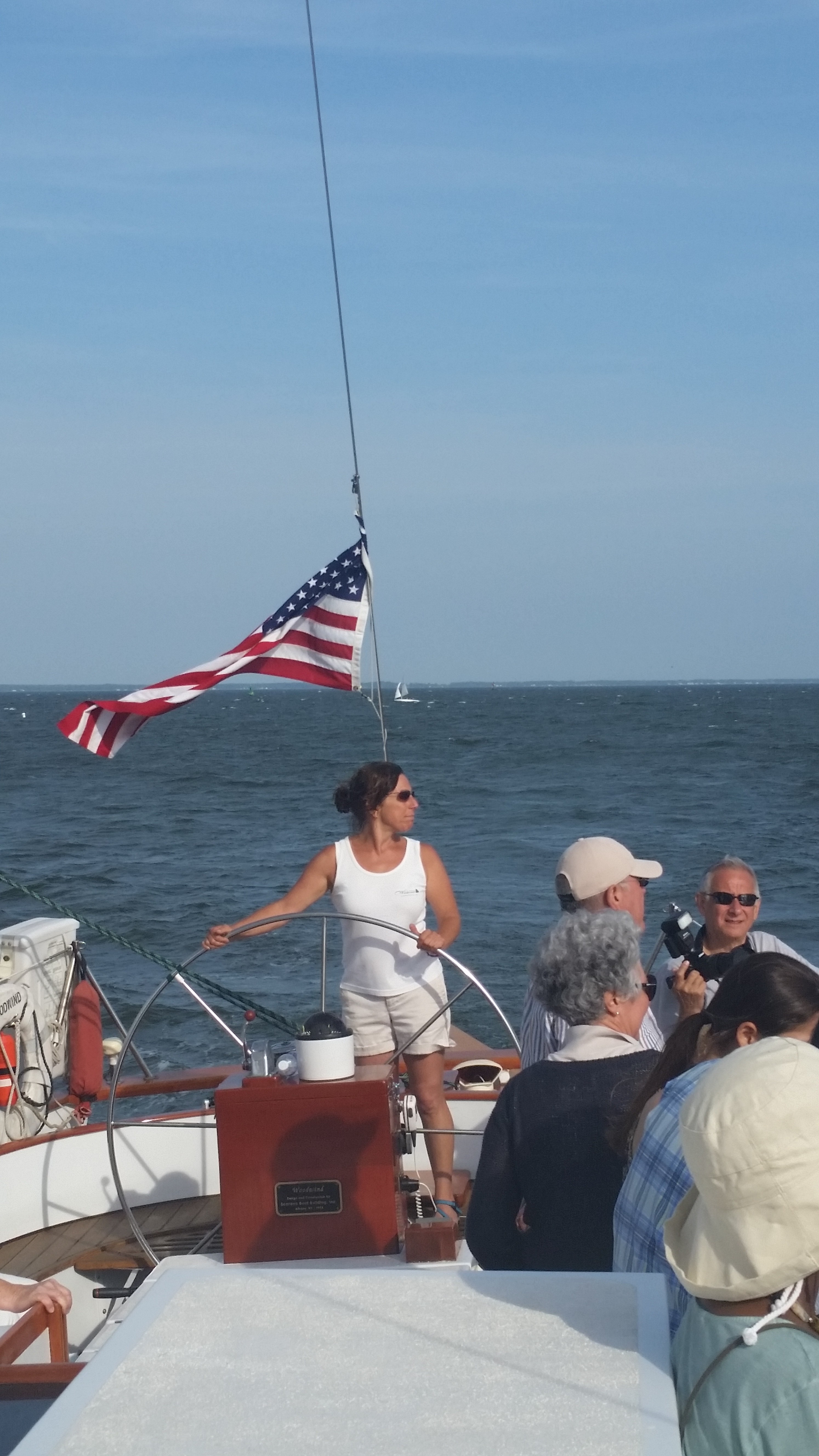 Captain steering schooner and pointing out sights on the way to guests