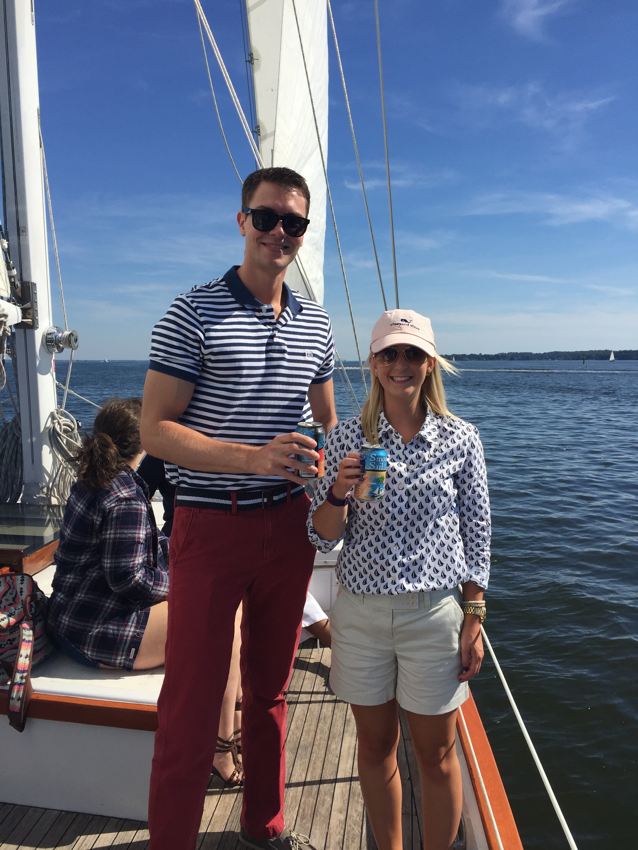Couple holding up beverages on a beautiful blue sky day sailing