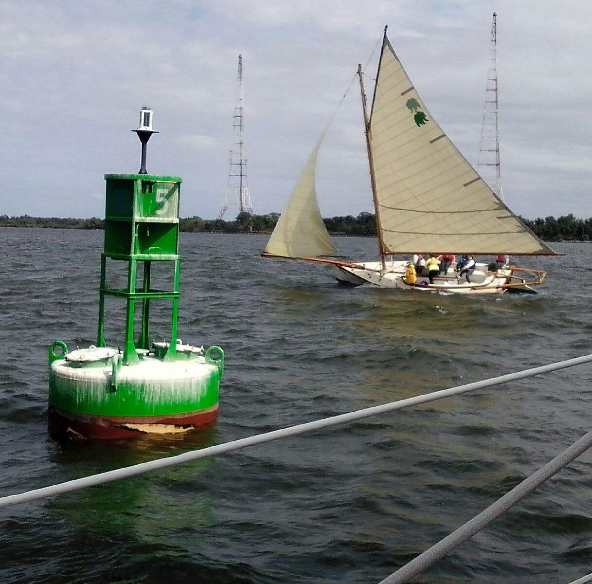 A sailboat racing in the Wooden Boat Regatta sailing around a marker