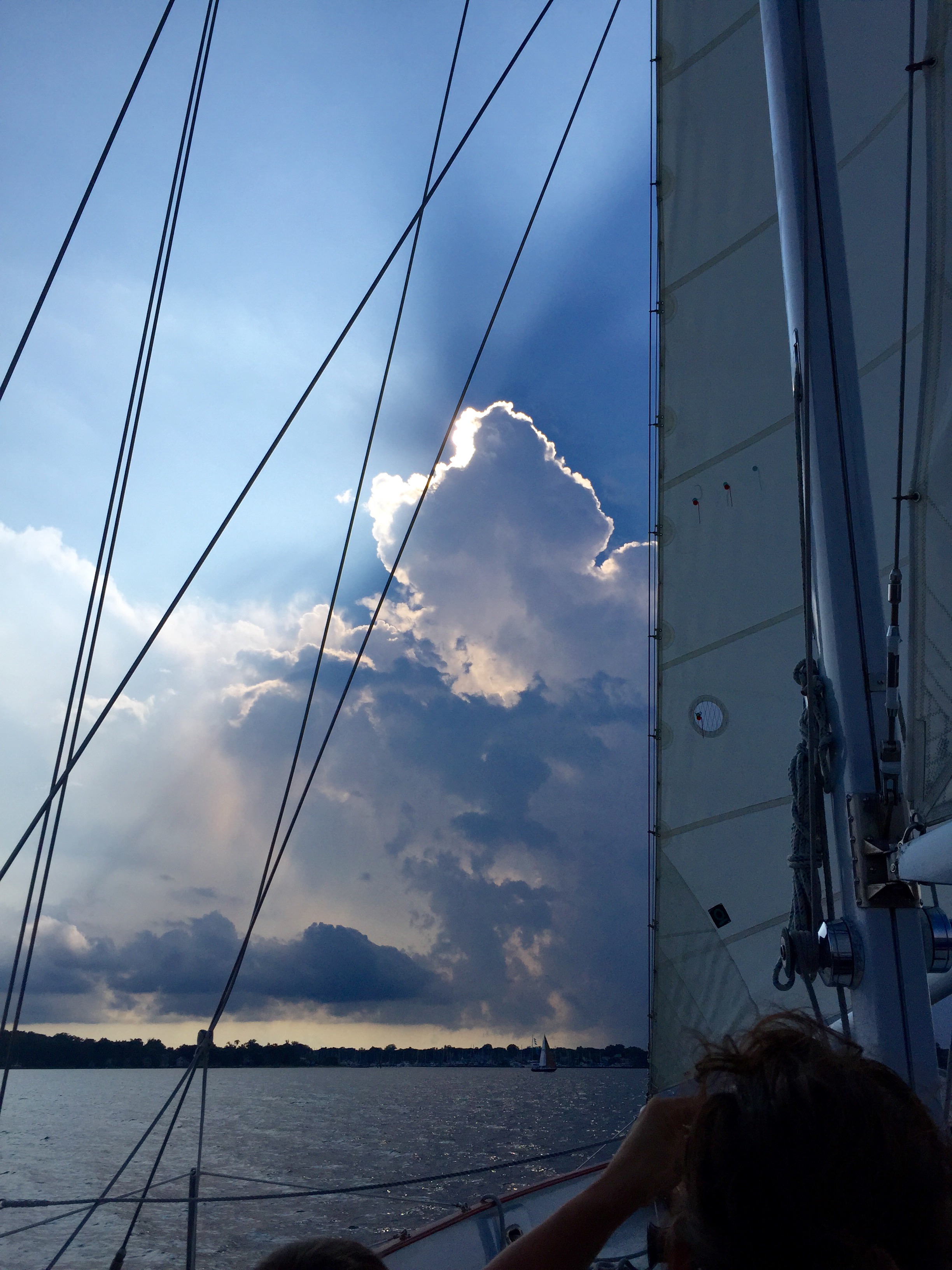Dark cloud with sun peering out over it looking through sails