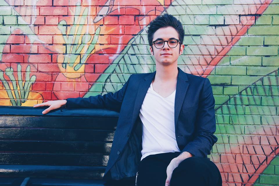 Entertainer Paul Pfau sitting on a bench in front of art work