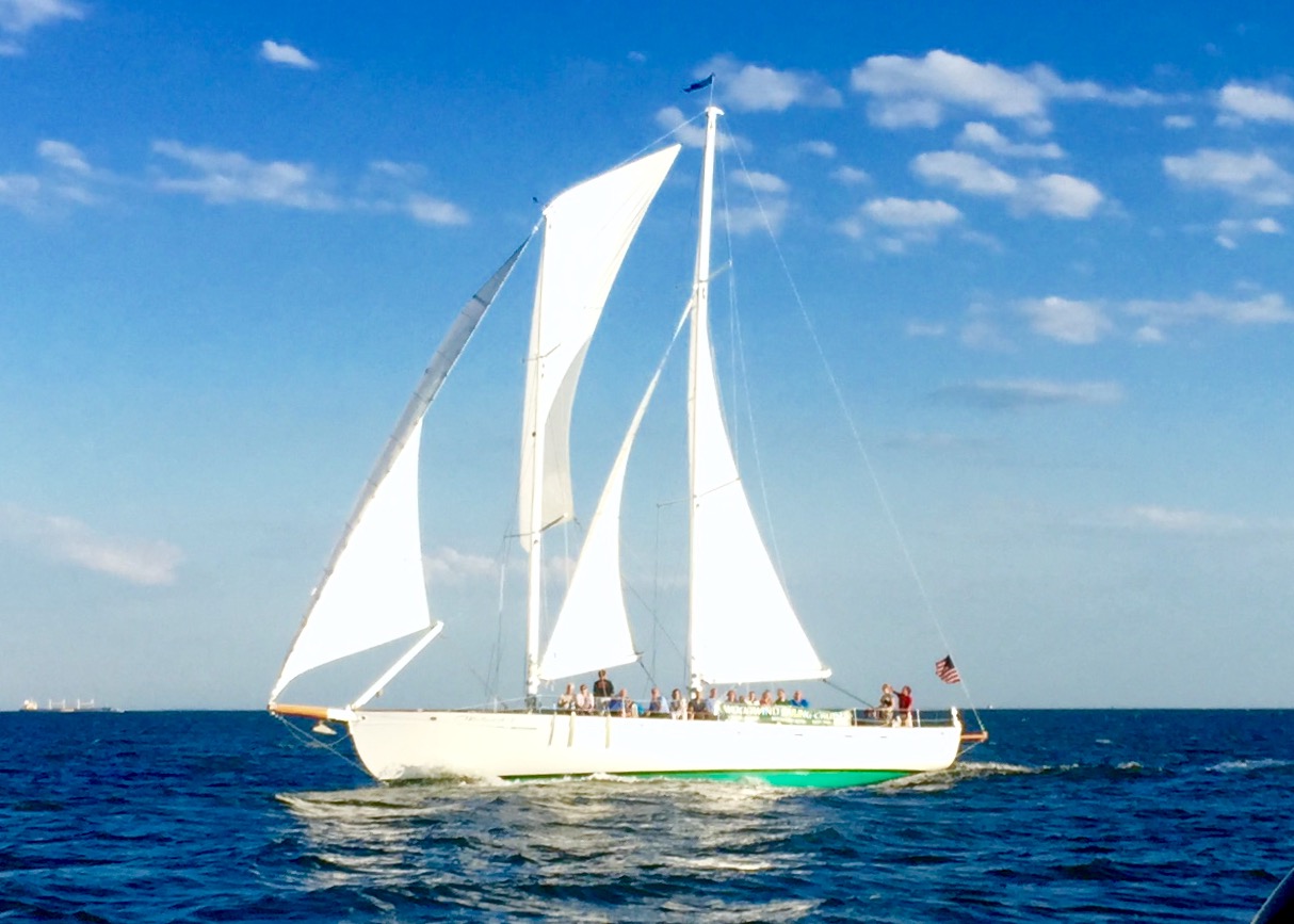 White schooner sailing against a bright blue sky and waters