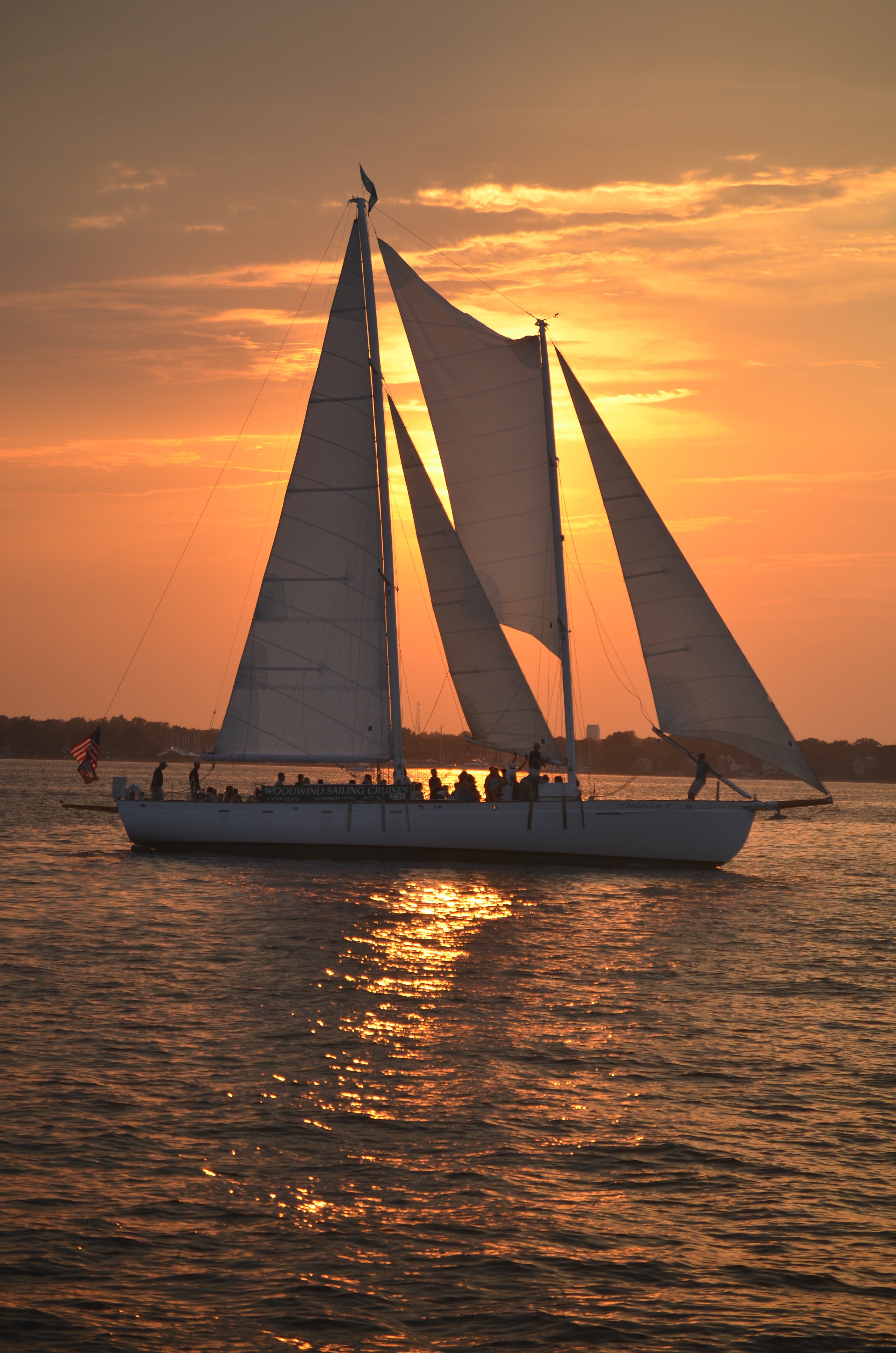 Orange streaked sky and reflecting in waters around schooner sailing