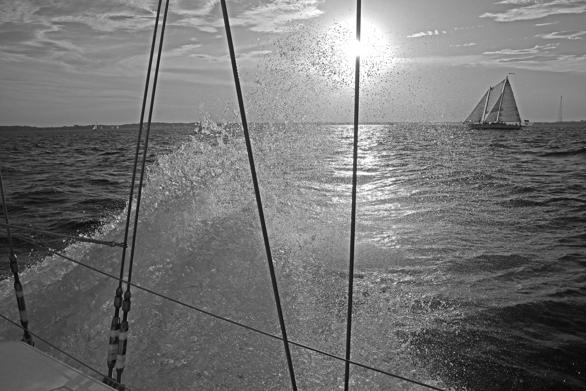 Black and white salt water spraying from boat into the sun