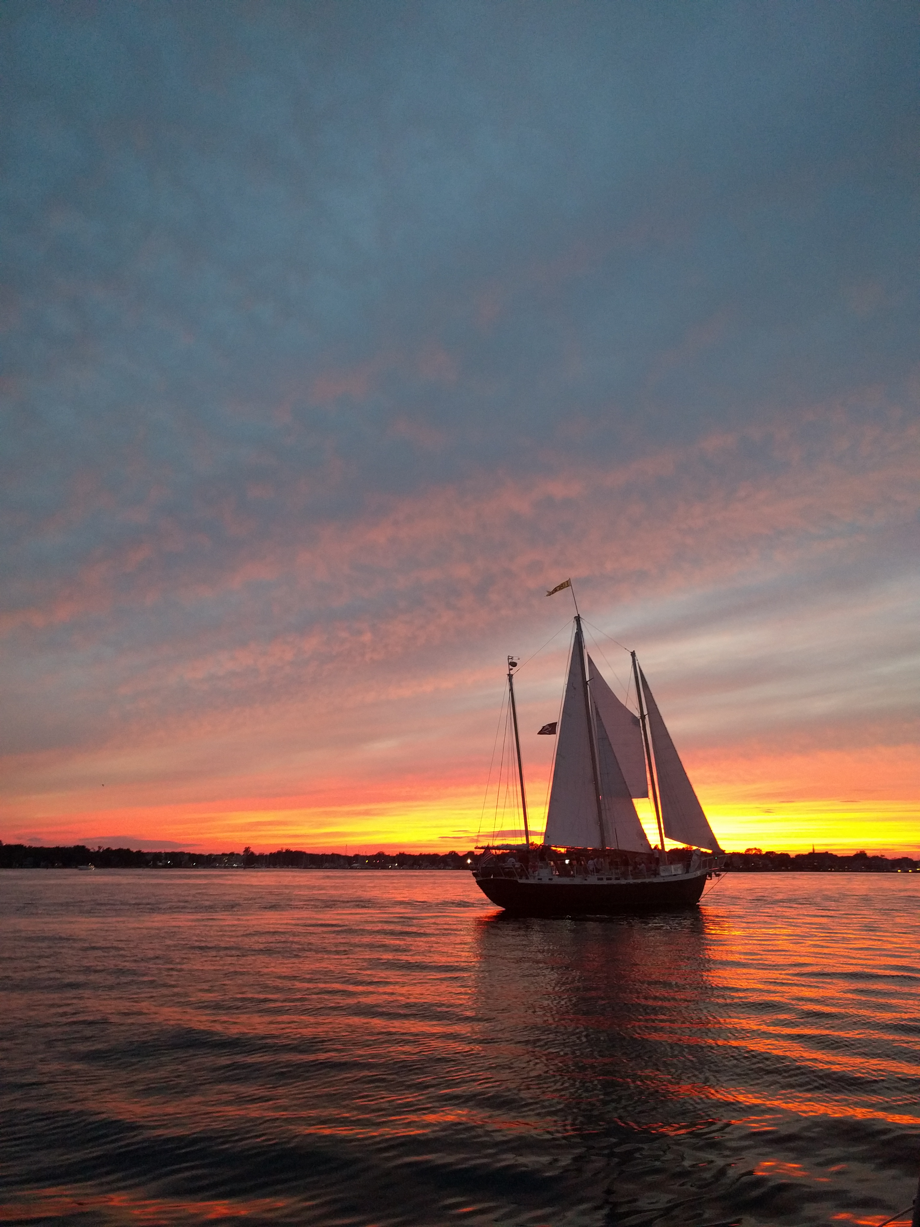 Streaked Blue, pink and orange sky reflecting on water around the schooner