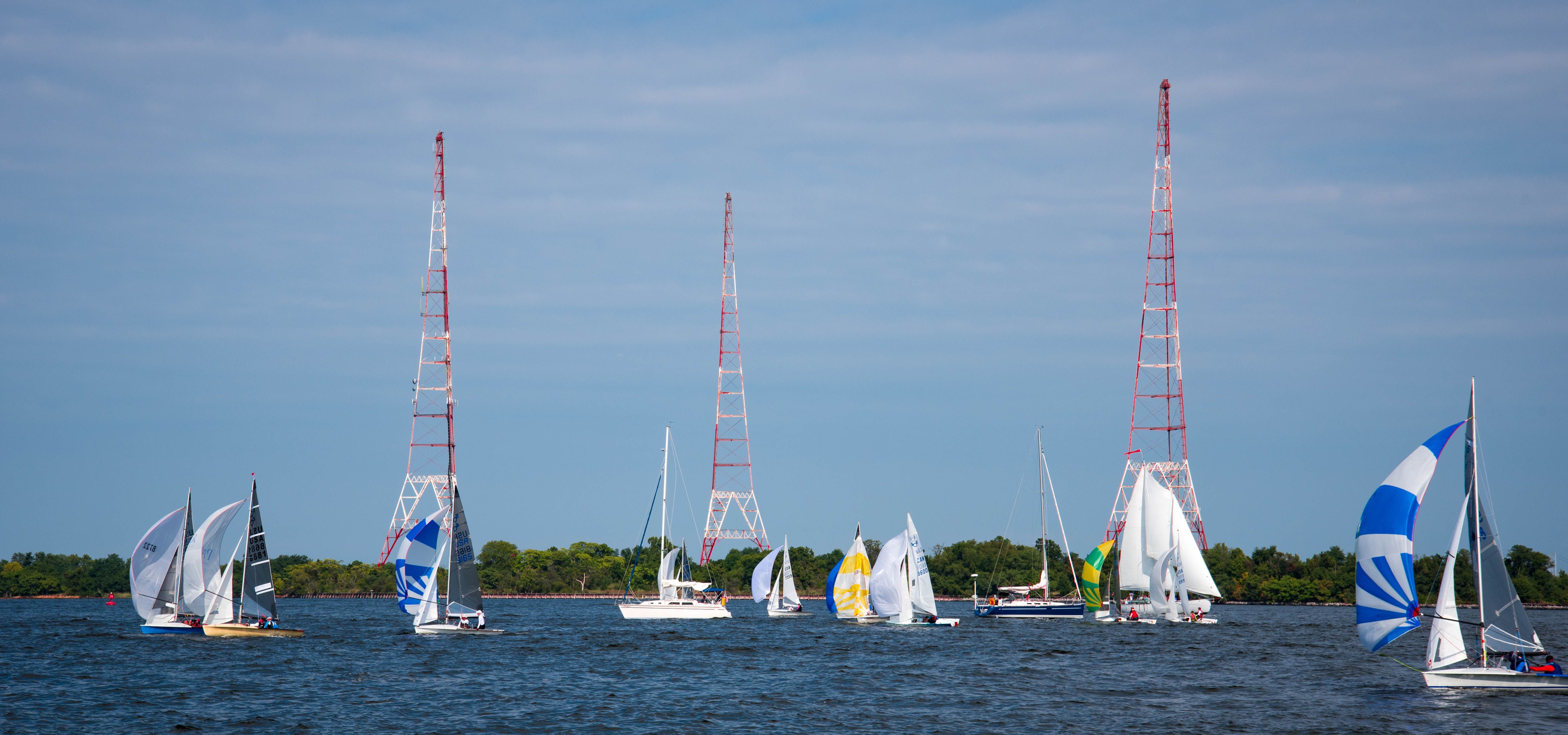 Sailboats with colorful sails sailing in front of red and white towers