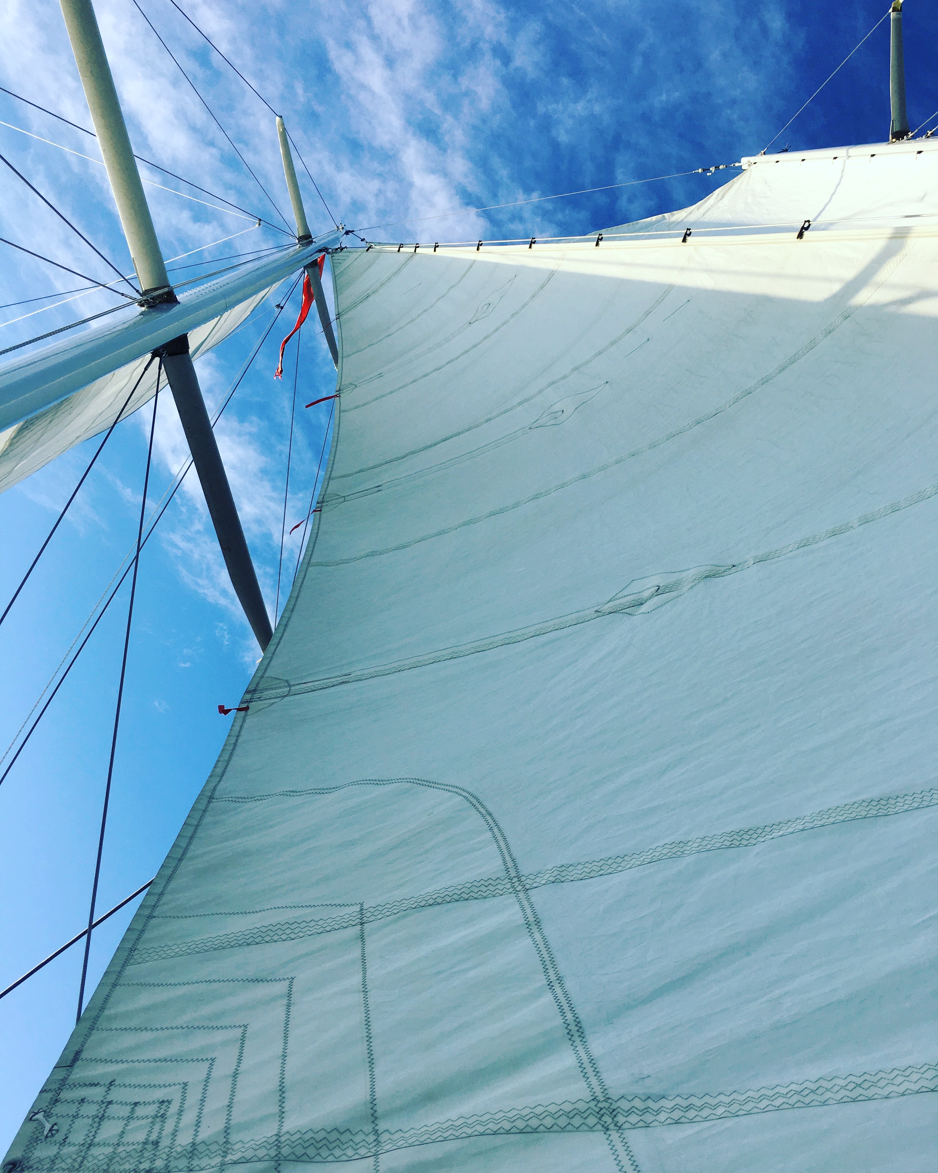 Looking straight up the schooner sails in to blue and white sky