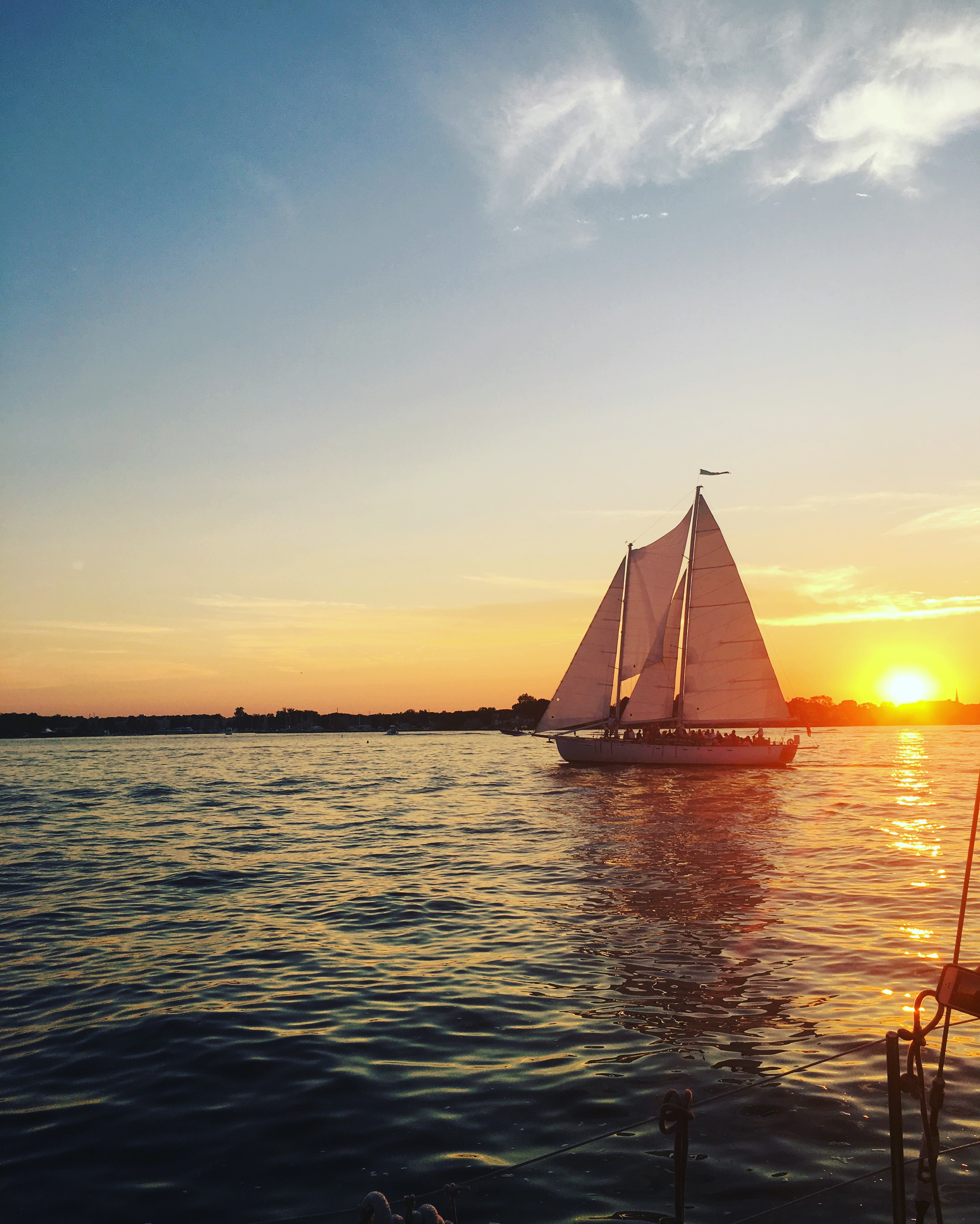 Schooner sailing by bright ball of the sun along the skyline