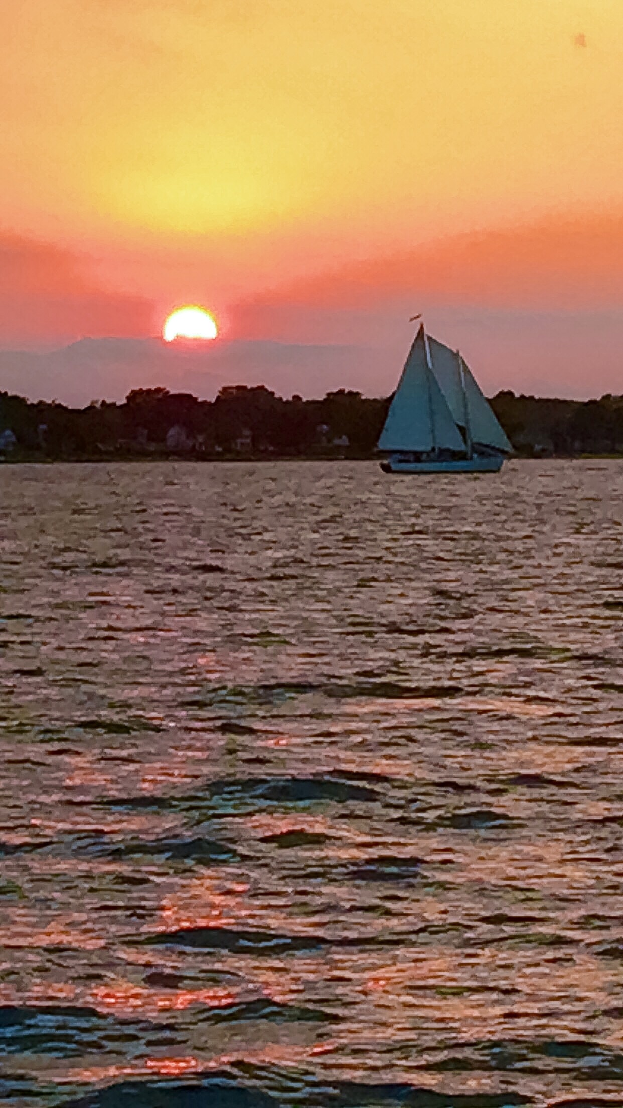 Beautiful Orange, pink and yellow sunset with schooner sailing by