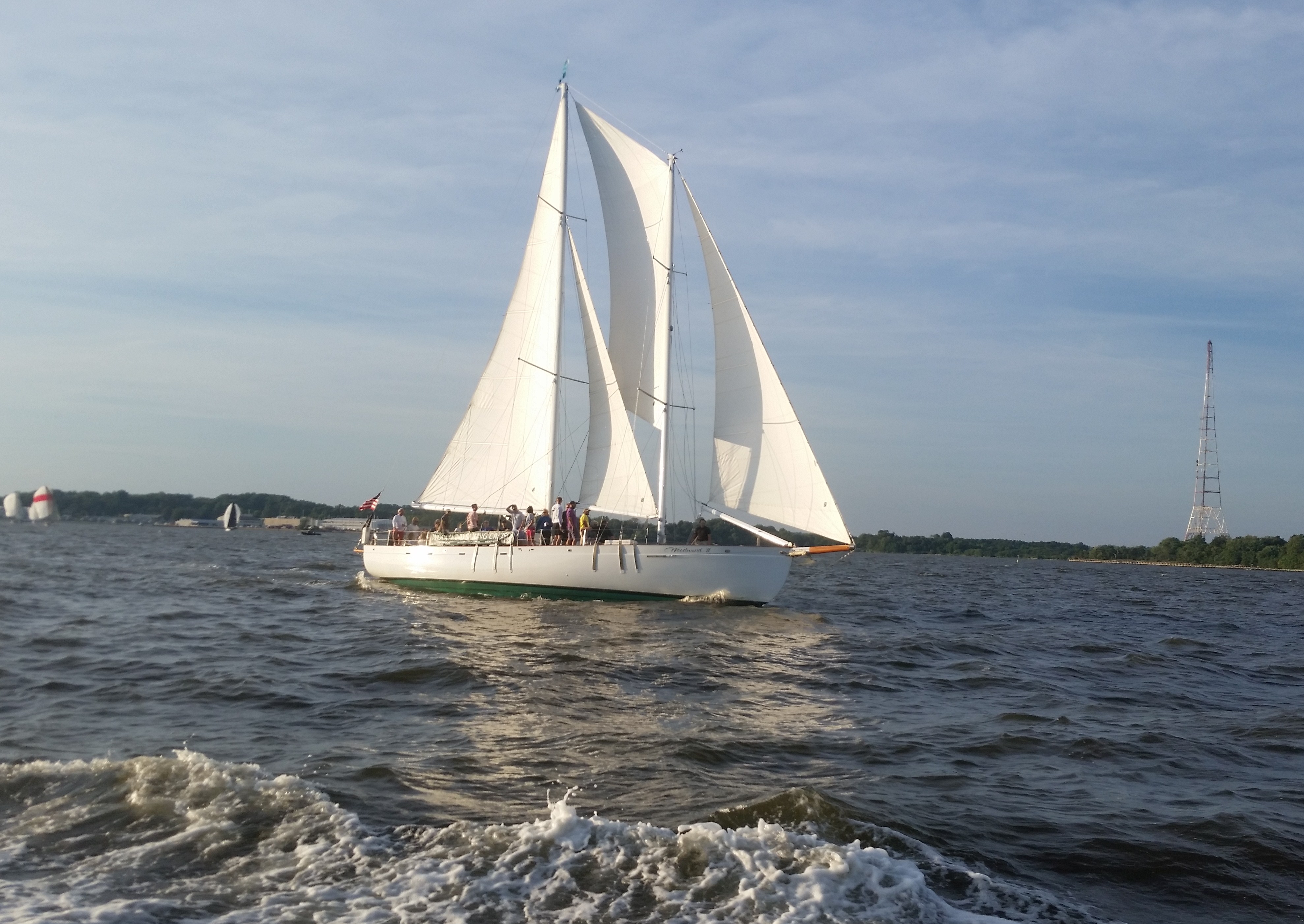 White sails full of wind on as the schooner flies over the water