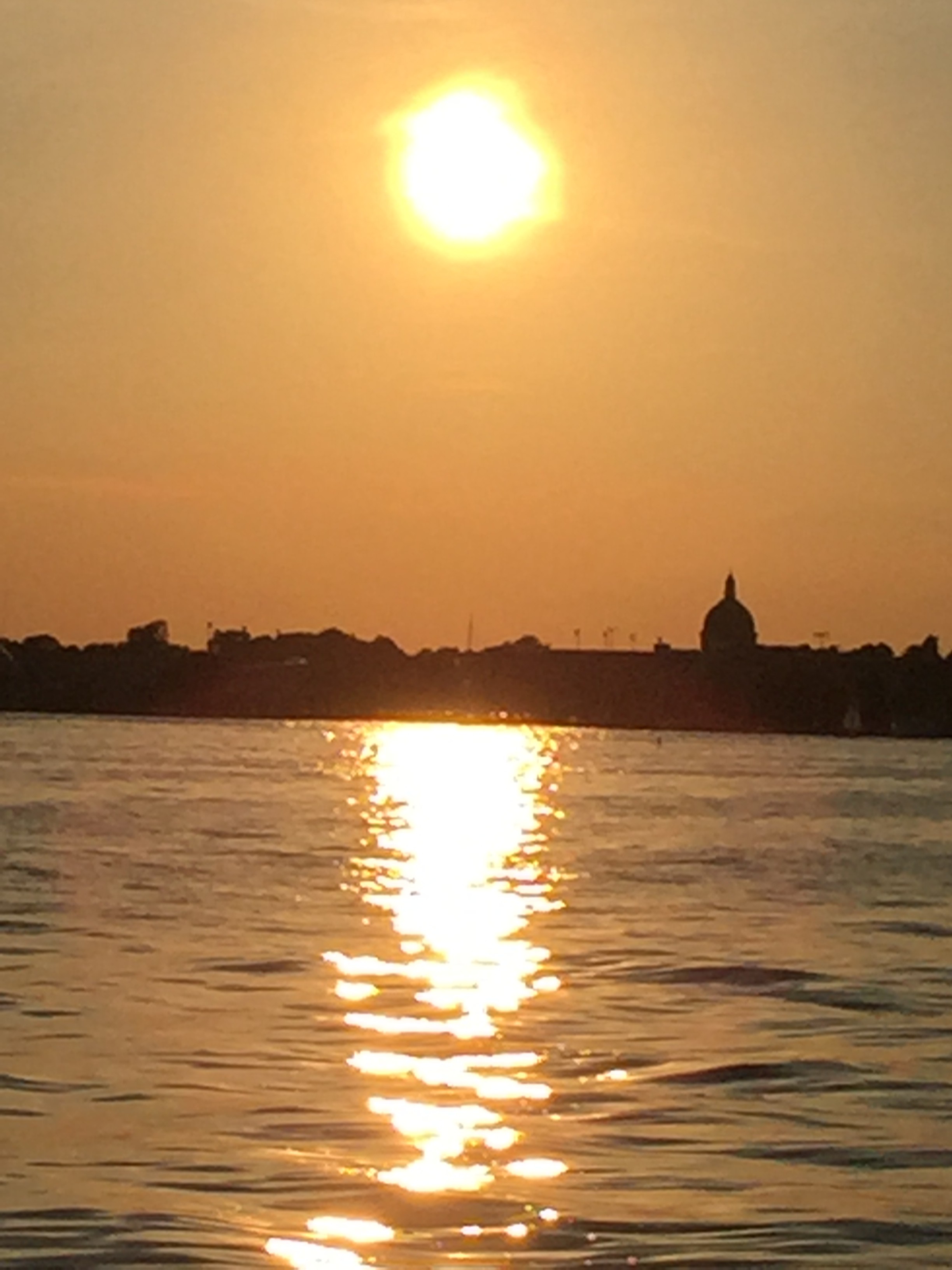 Bright yellow large sun shining over Annapolis and water