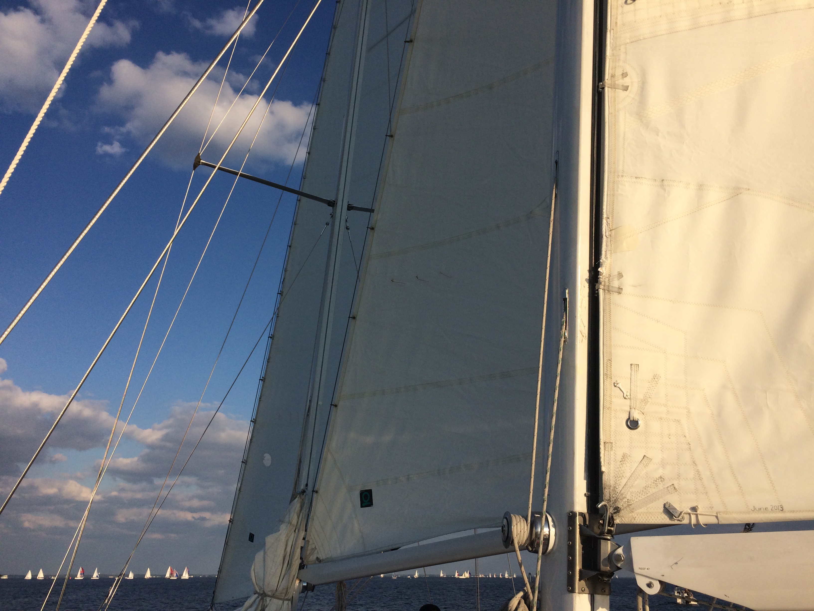 Looking through schooner sails at sailboats on the blue horizon