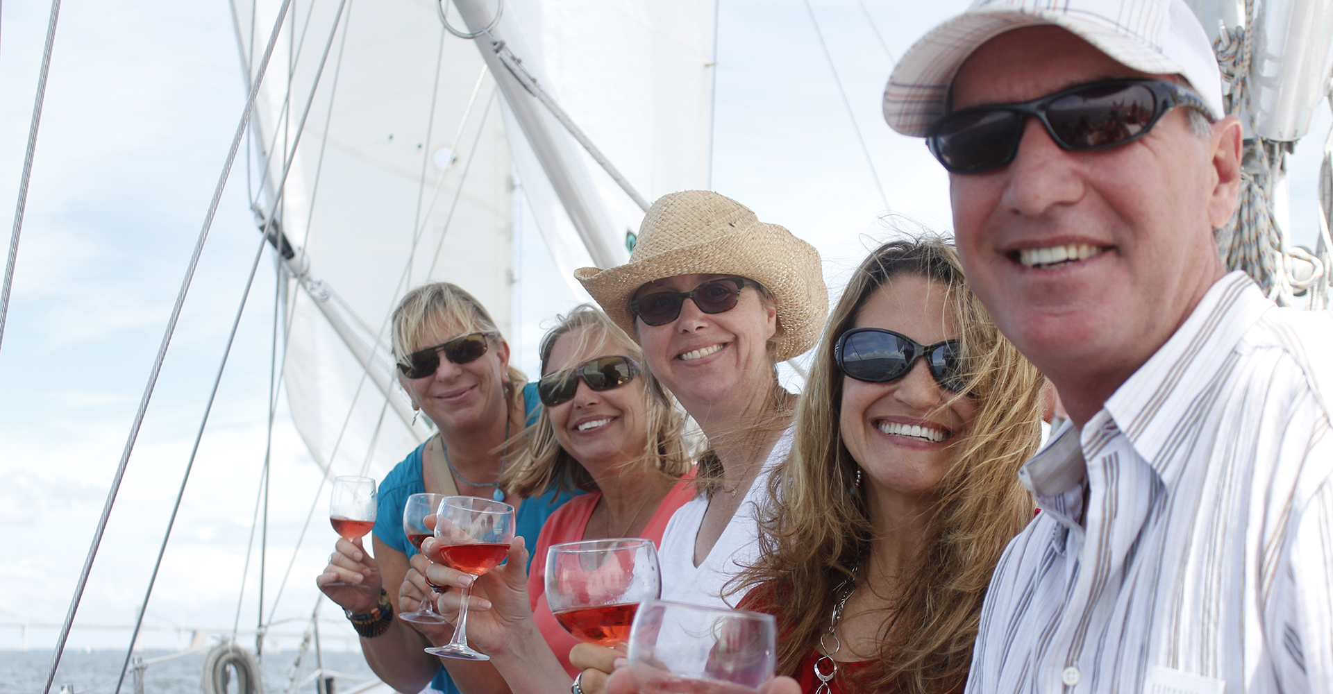 Guests with sunglasses and smiles enjoying glasses of wine on the boat