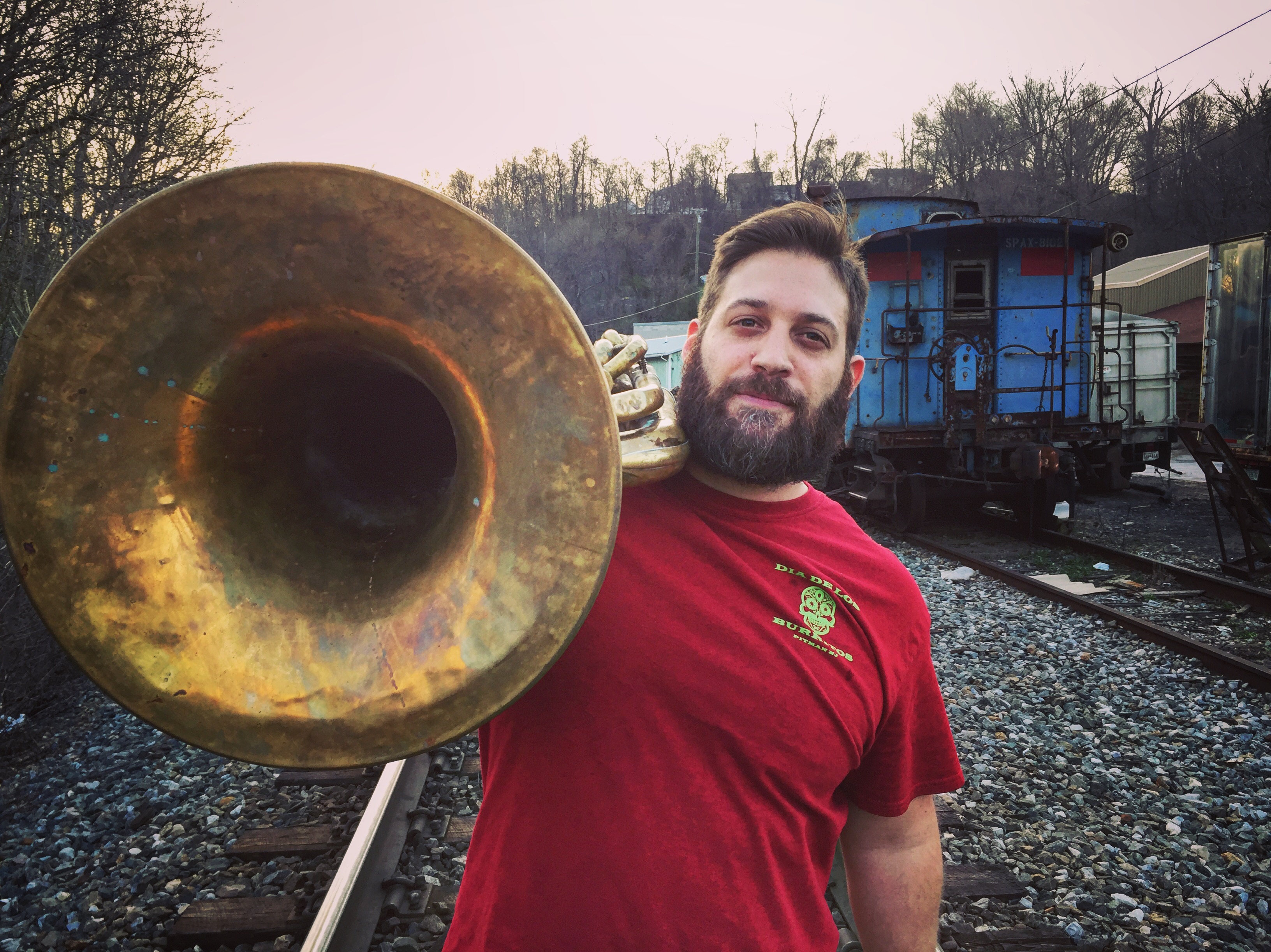 Jason Ager entertainer holding a tuba at a train yard