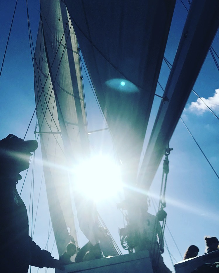 Looking up through schooner sails and rigging at bright sun