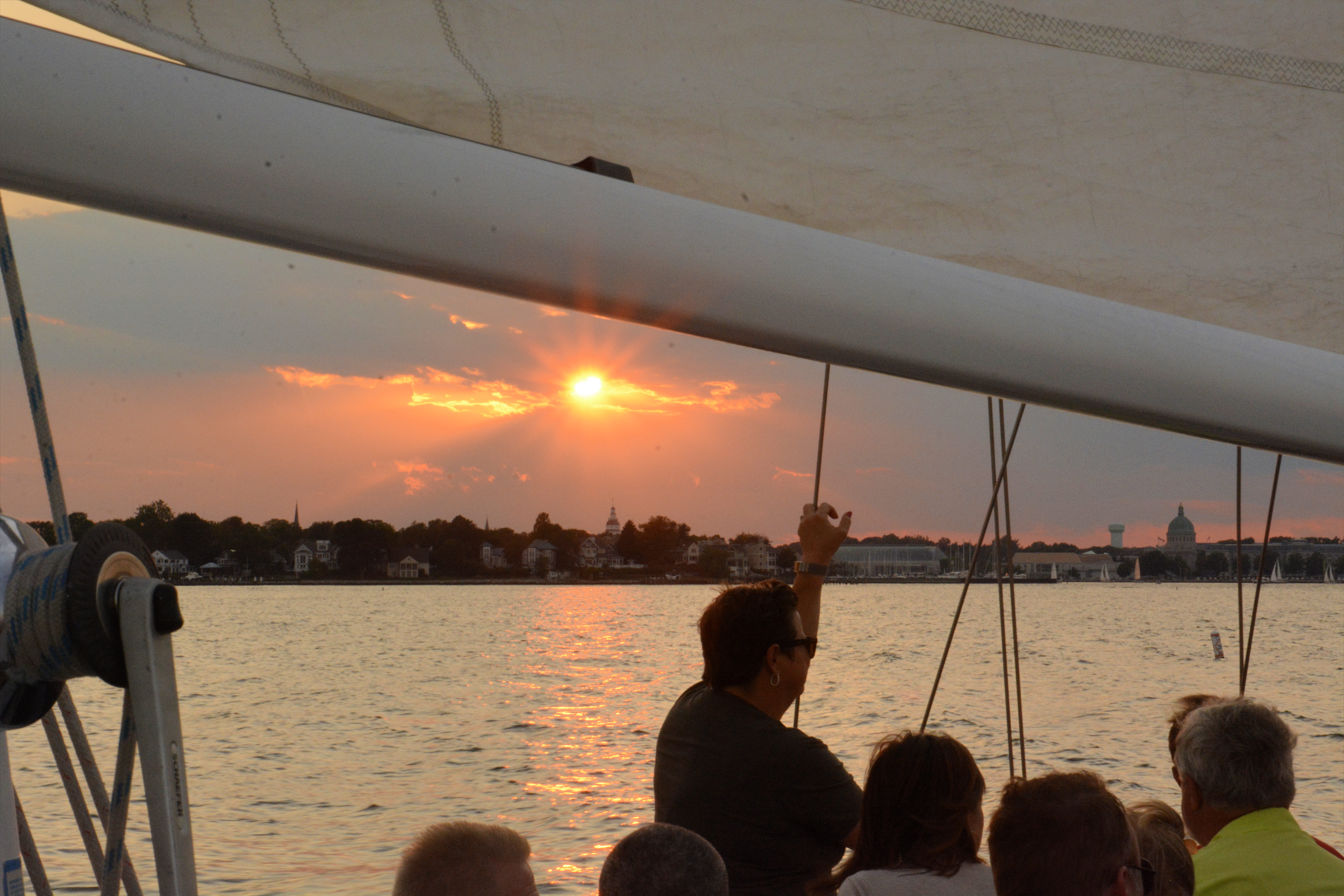 Guests looking on from boat as sunsets over Annapolis skyline