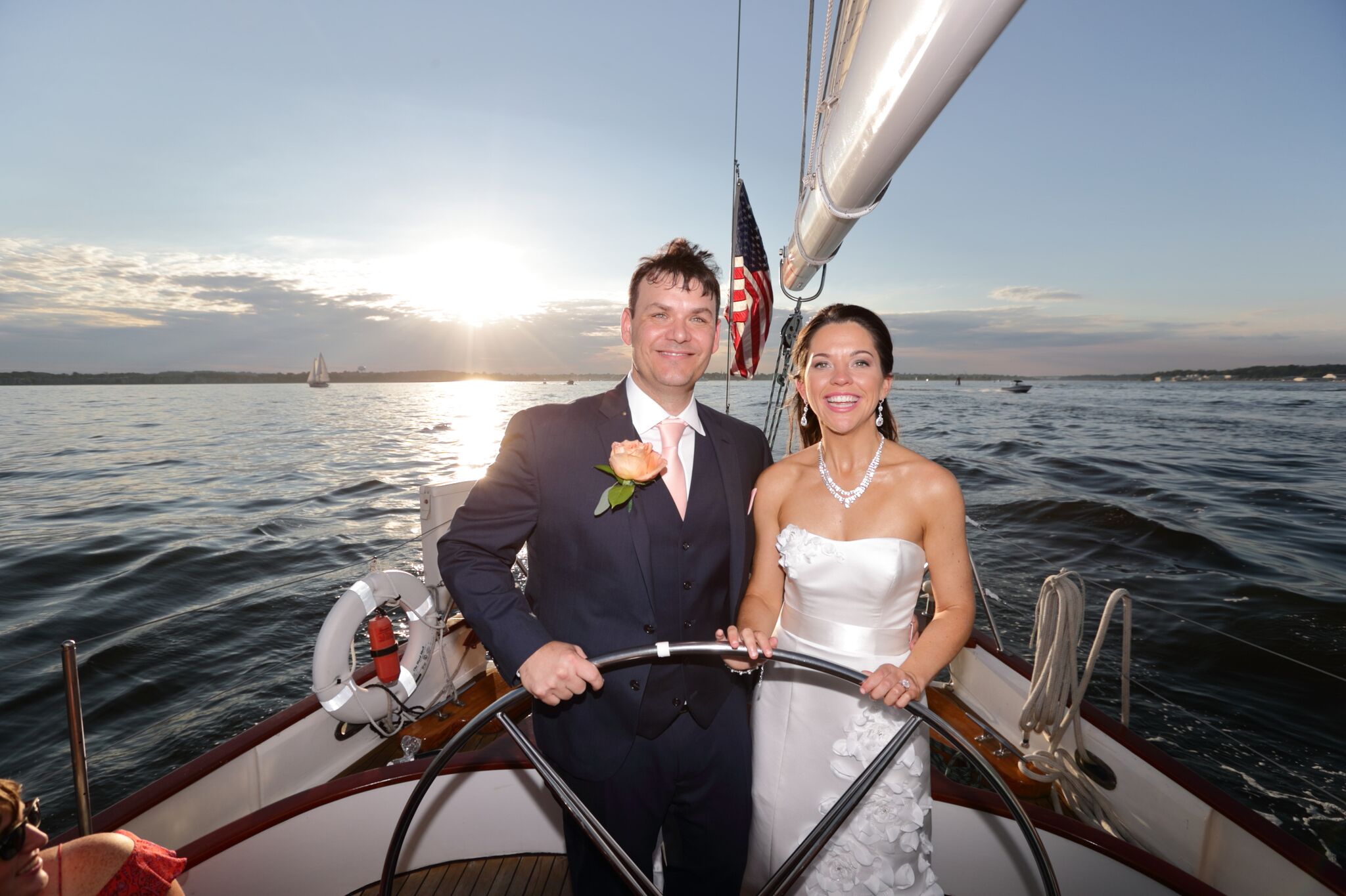 Bride and Groom steering the boat together with sunset behind them