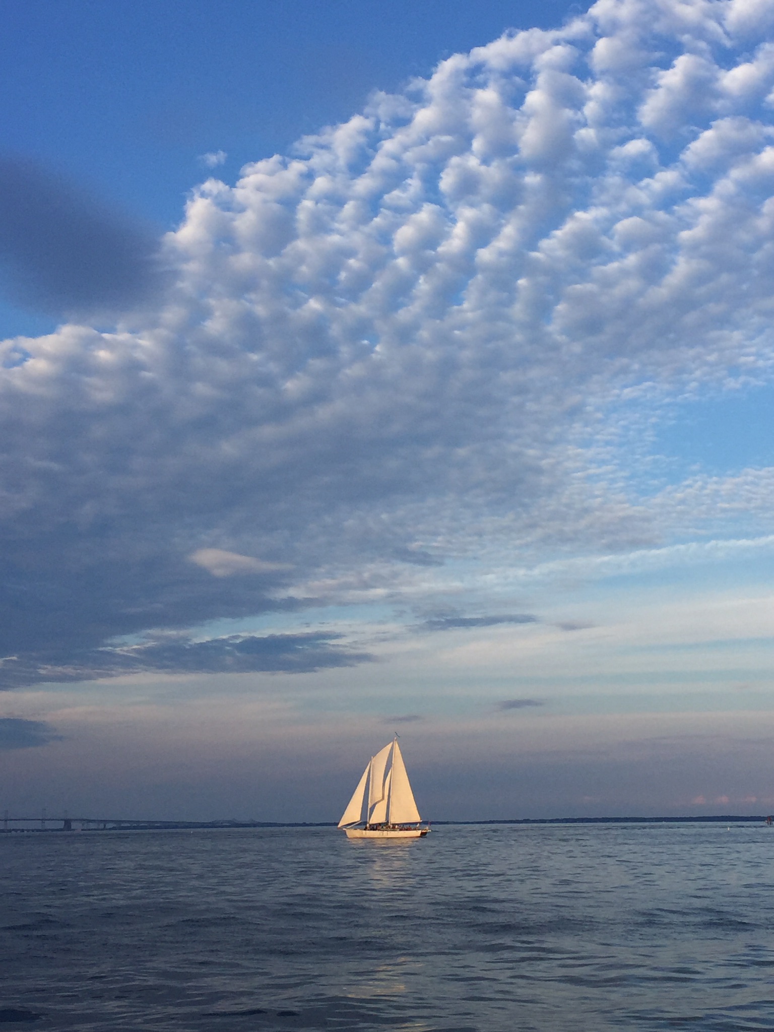 Schooner framed by blue water and purple and pink sky with clouds