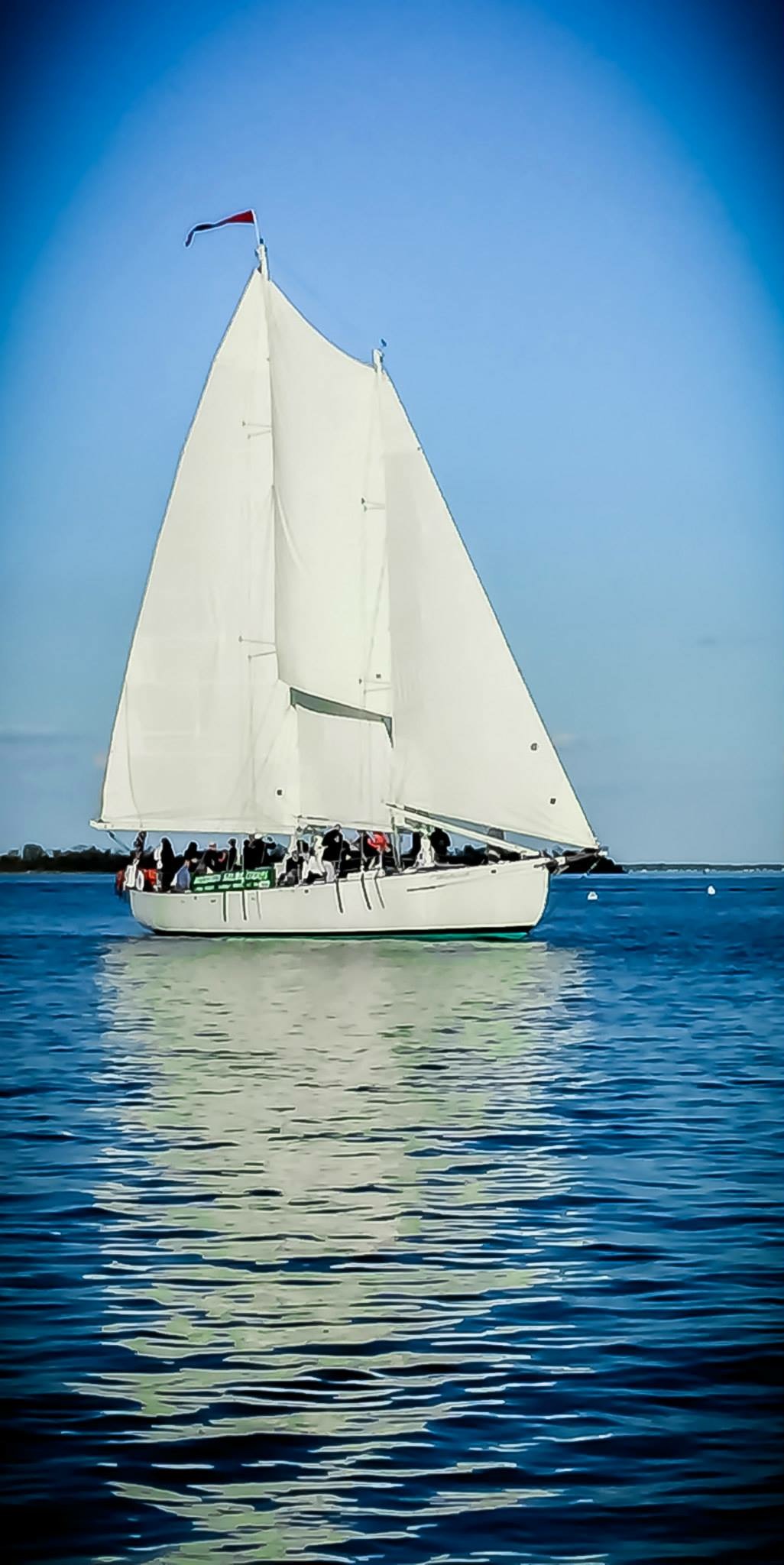 White Schooner standing out against bright blue sky and water