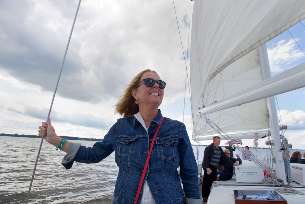 Women with jean jacket holding rigging and smiling into the wind