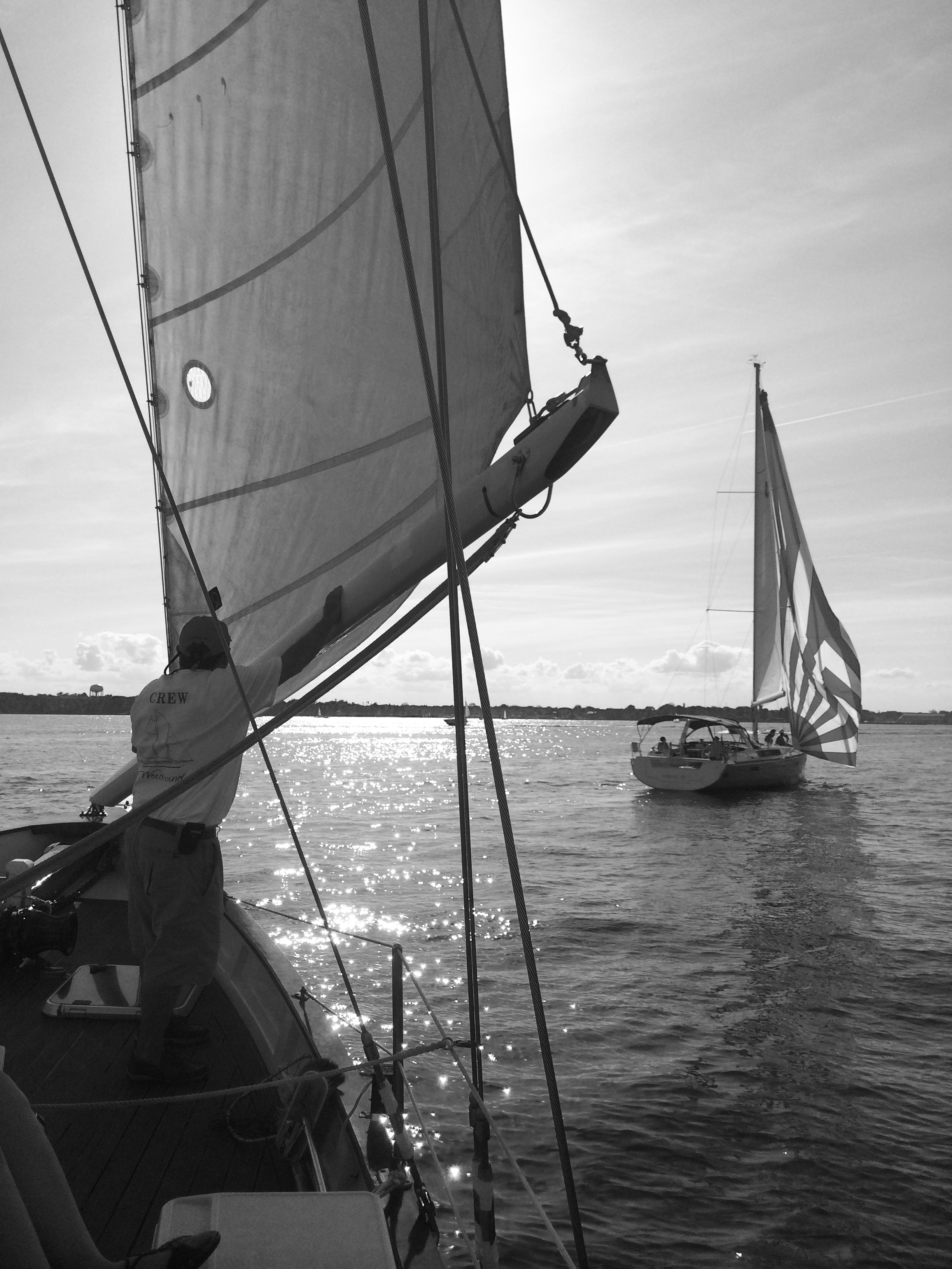 Black and white photo of schooner and a sailboat with sun on water